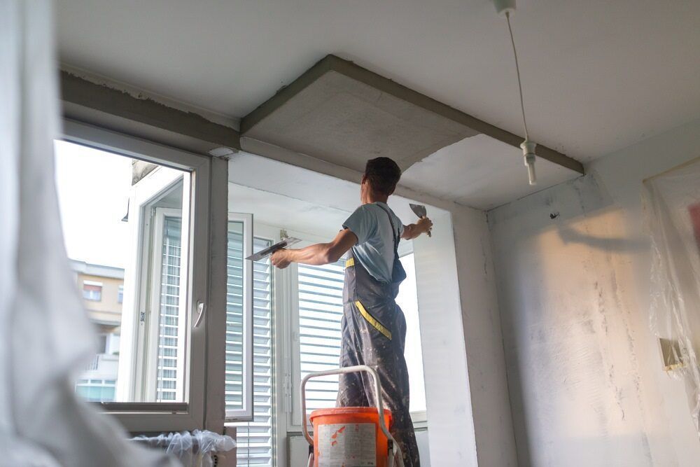 A Worker On A Ladder Plastering The Ceiling, Green Drywall Panels — HJK Plastering In South Lismore, NSW