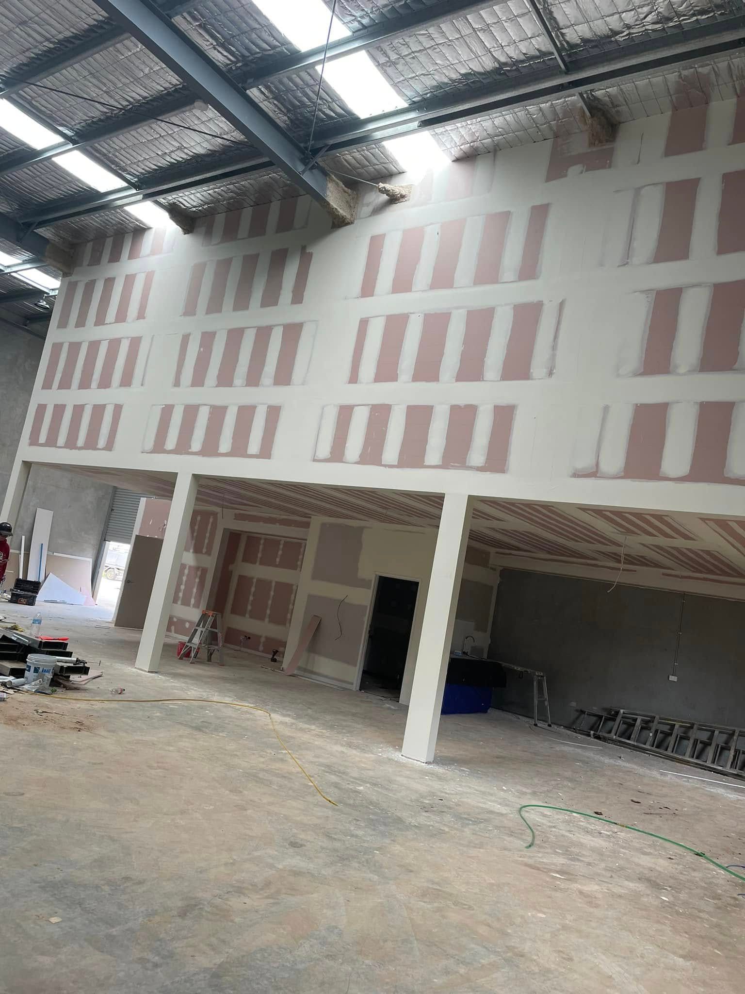 Interior Construction Site With A High Wall Partially Finished With Drywall Panels — HJK Plastering In South Lismore, NSW