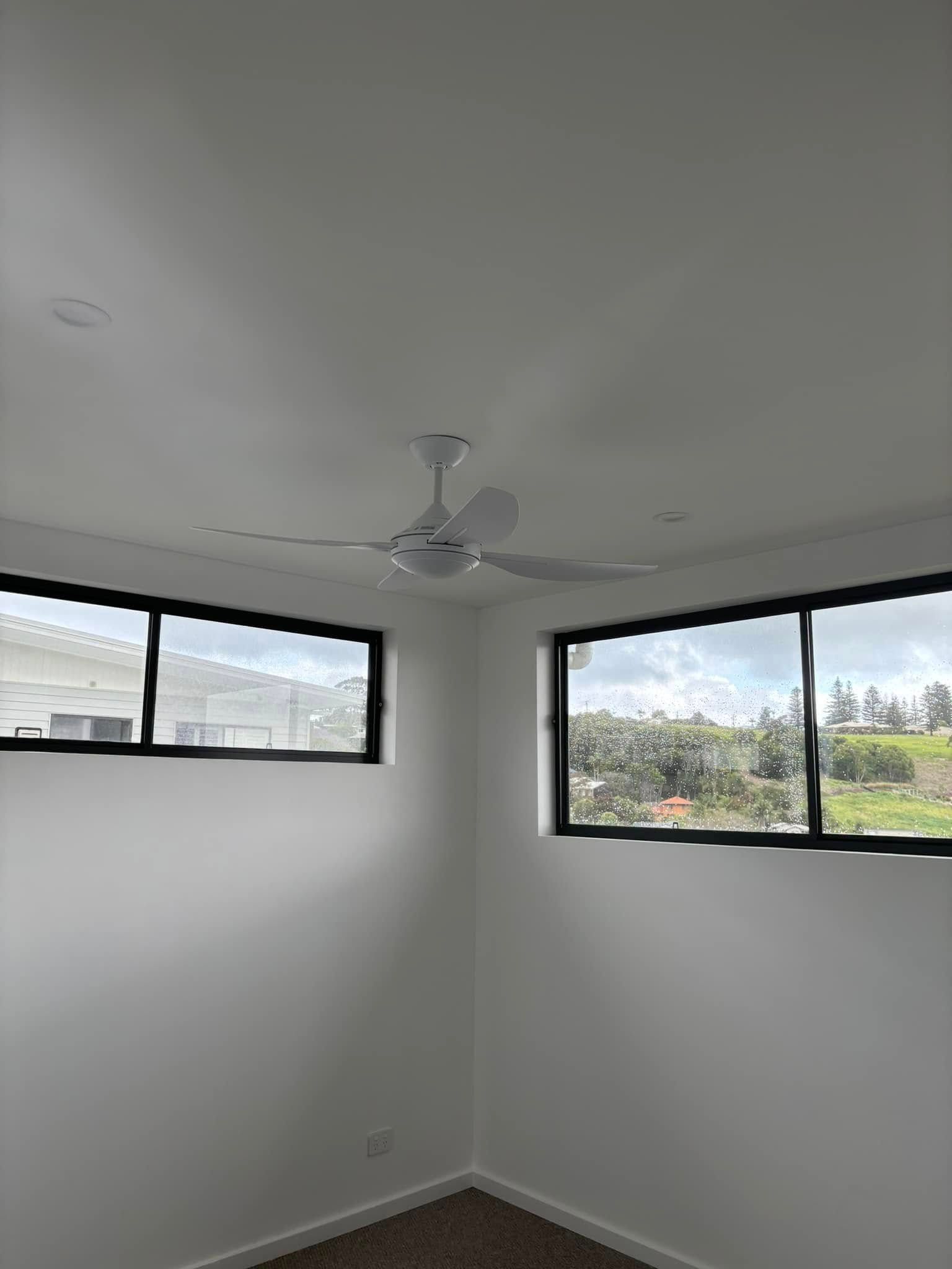 A Room Corner With White Walls, A Ceiling Fan, And Two Black-framed Windows — HJK Plastering In South Lismore, NSW