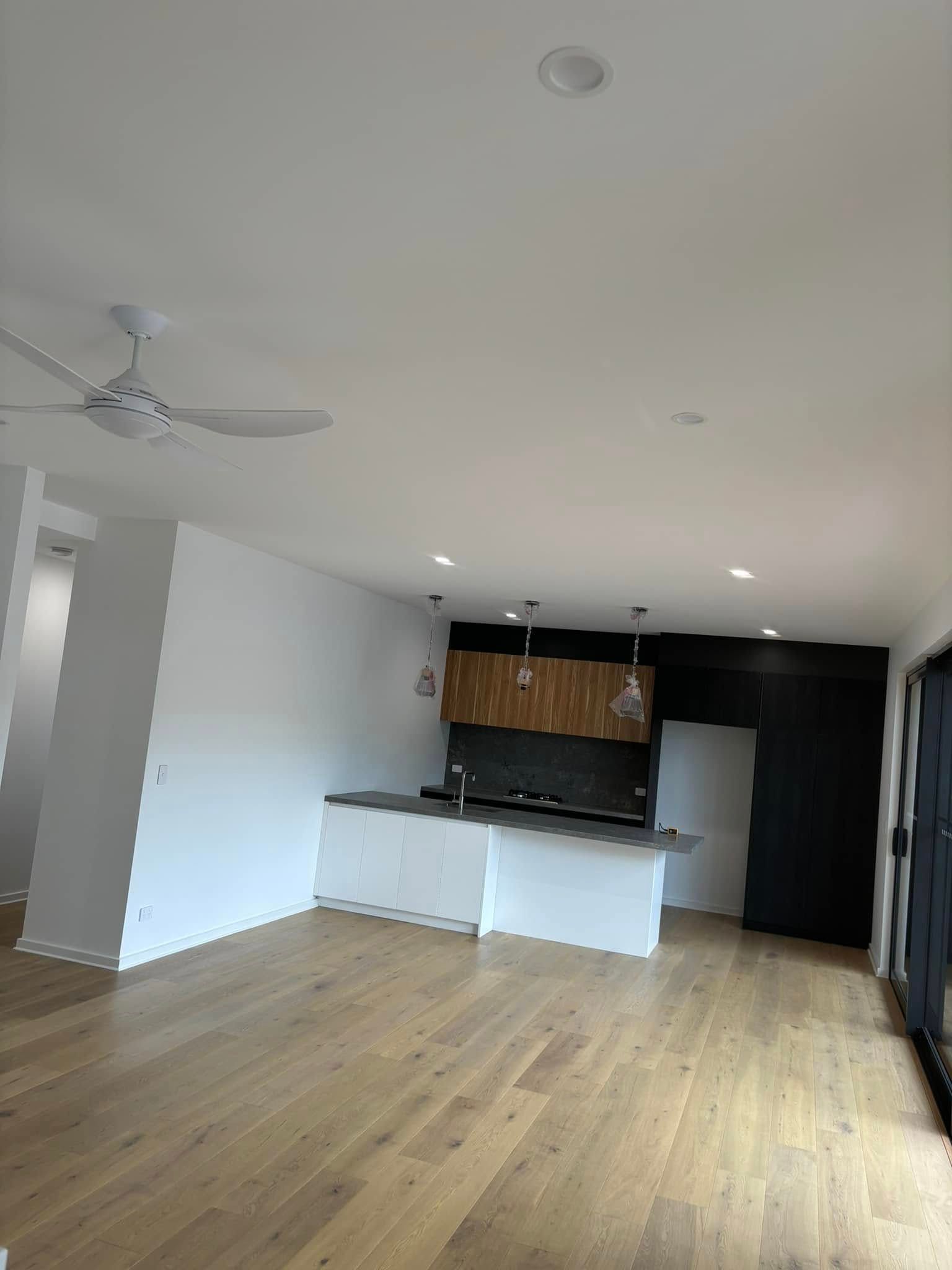 An Open-plan Living Area With Light Wood Flooring And A White Kitchen Island — HJK Plastering In South Lismore, NSW