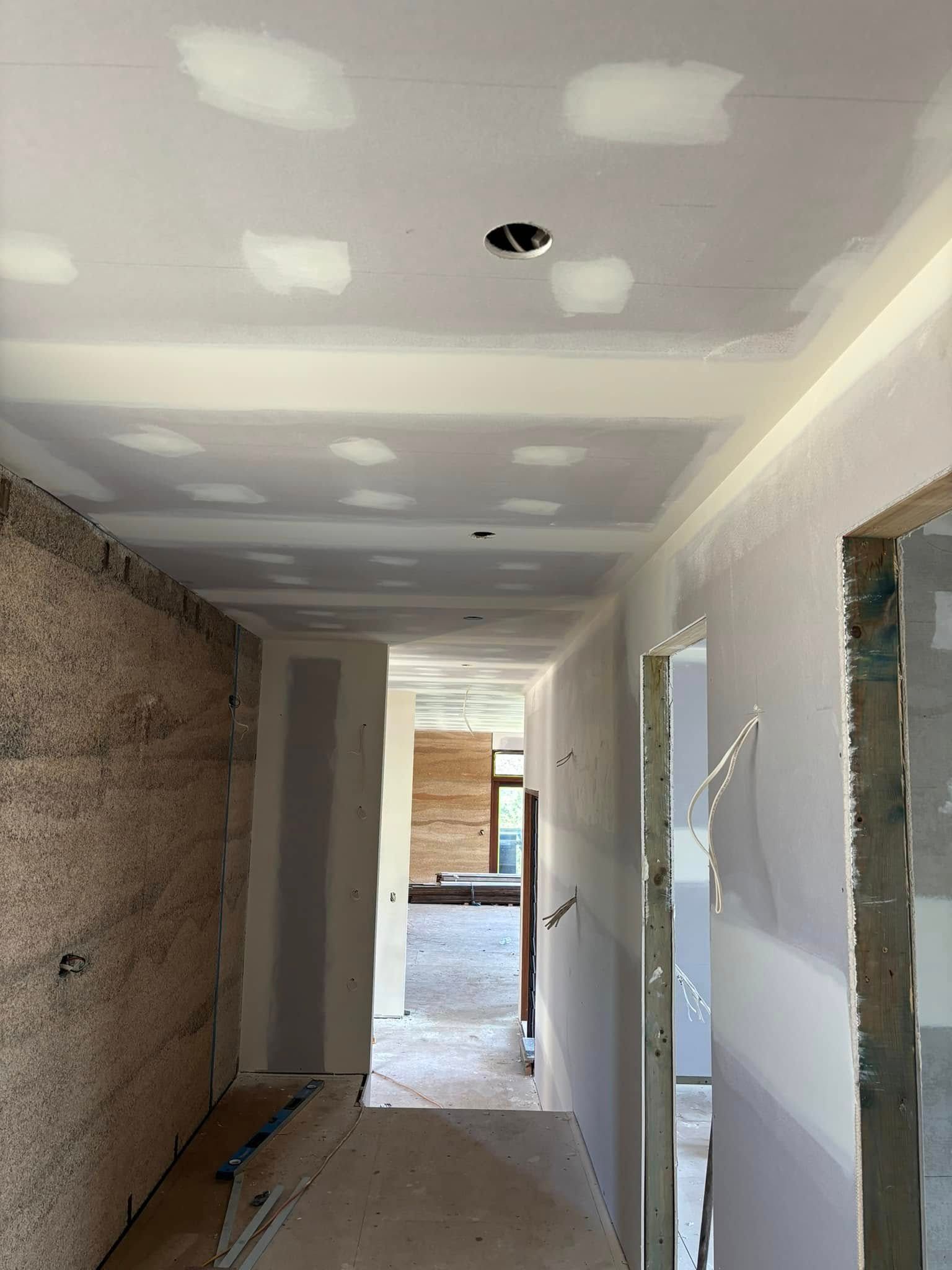 A View Looking Down A Hallway Under Construction With Unfinished Drywall — HJK Plastering In Ballina, NSW