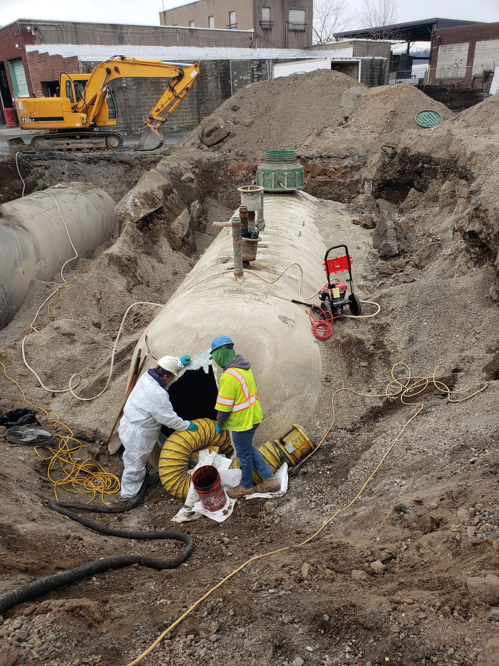 A group of construction workers are working on a large gas tank.