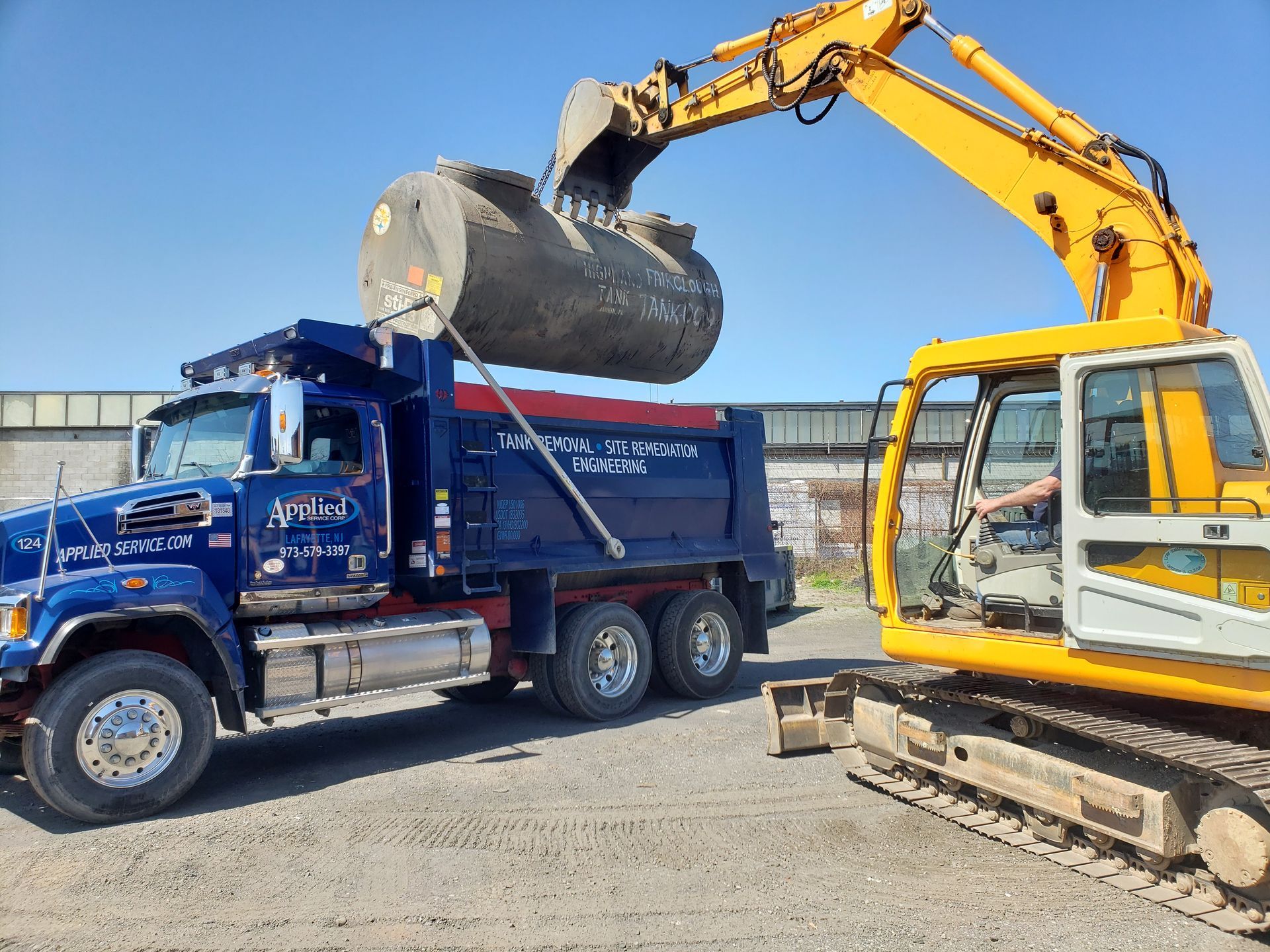 A dump truck is being loaded with dirt by a yellow excavator.