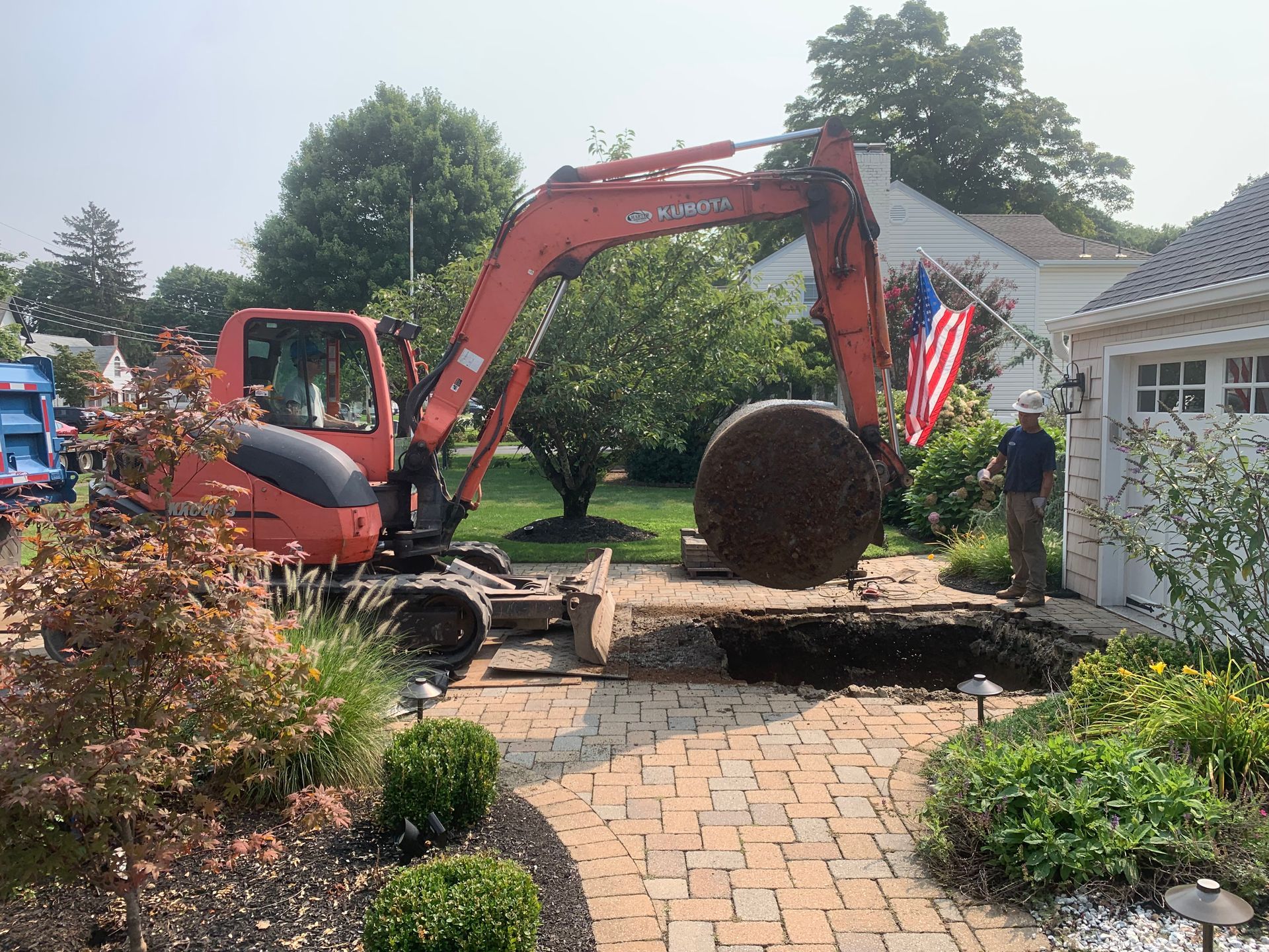 An excavator is digging a hole in the ground in front of a house.