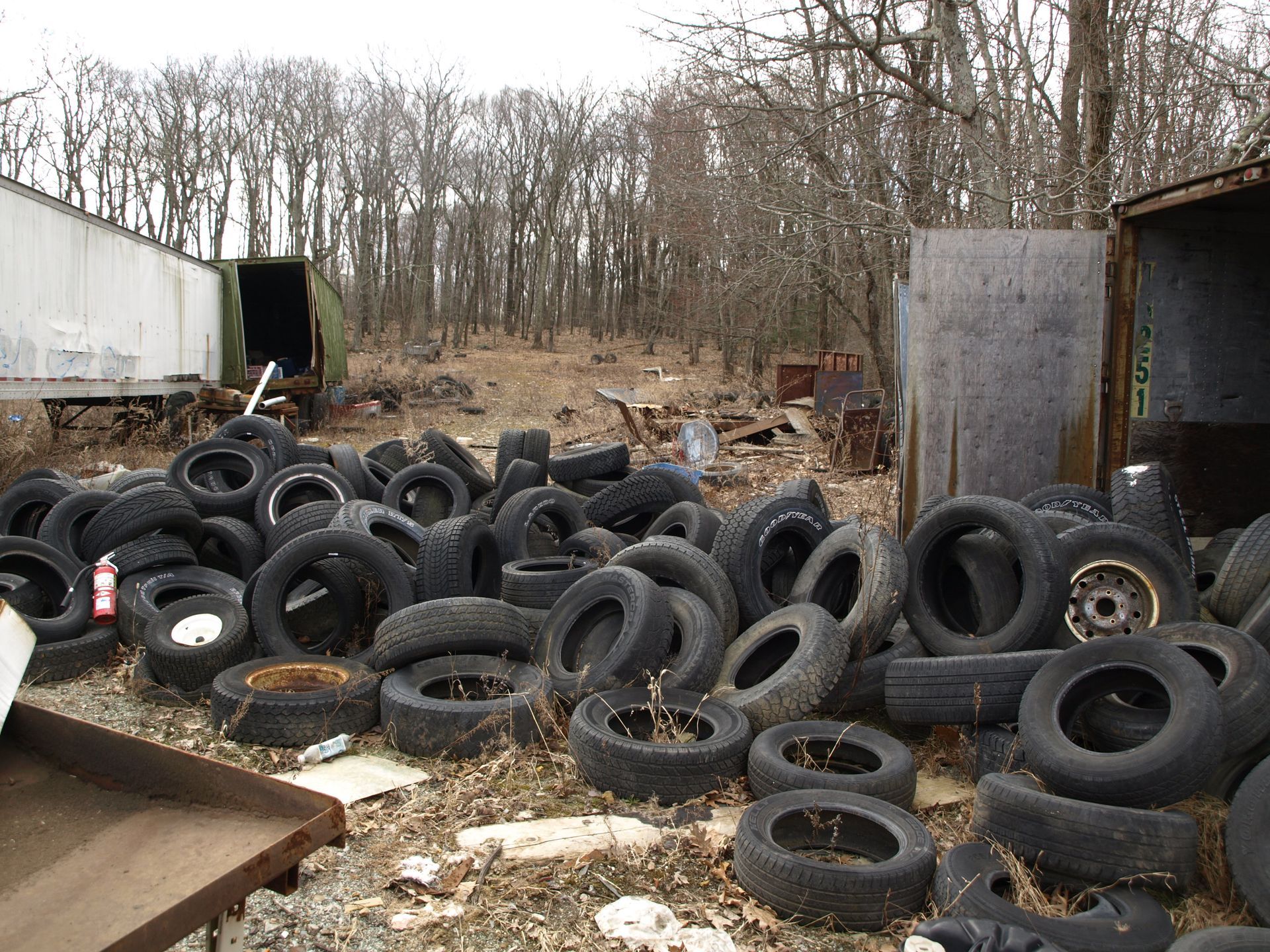 A pile of old tires are stacked on top of each other in a field.