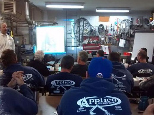 A group of men are sitting in a classroom wearing applied shirts