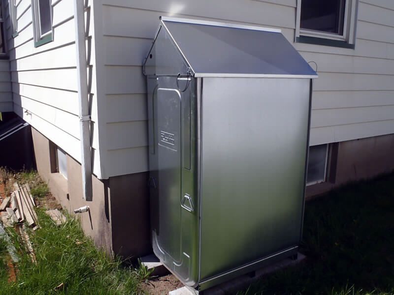 A stainless steel shed sits on the side of a house