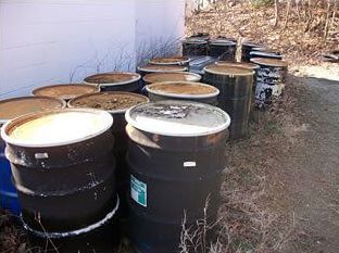 A bunch of barrels are stacked on top of each other on the ground.