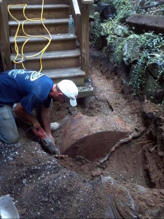 A man is digging a hole in the dirt in front of stairs.