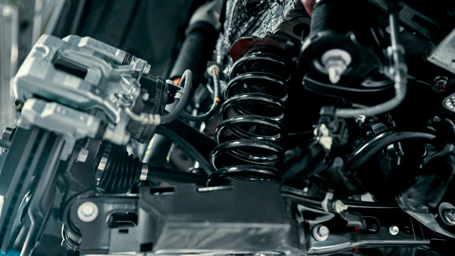 Close-up of a car's suspension system with a silver brake, black coil spring, and various components.