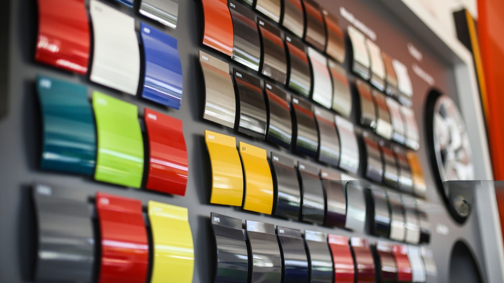 A wall display showcasing a variety of car paint color samples, ranging from red and blue to silver and black.