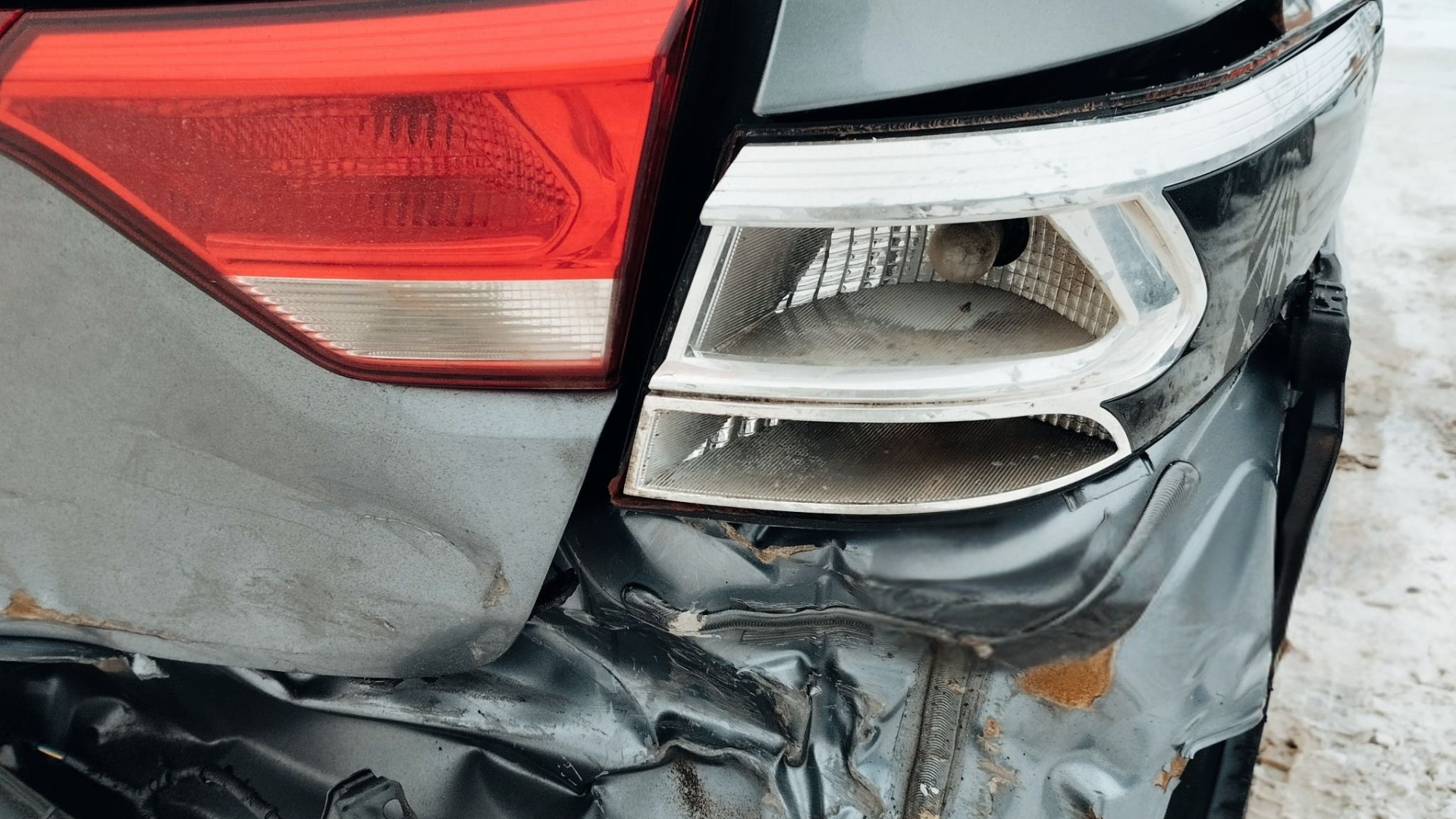 Damaged car rear end; broken tail light and crumpled bumper.