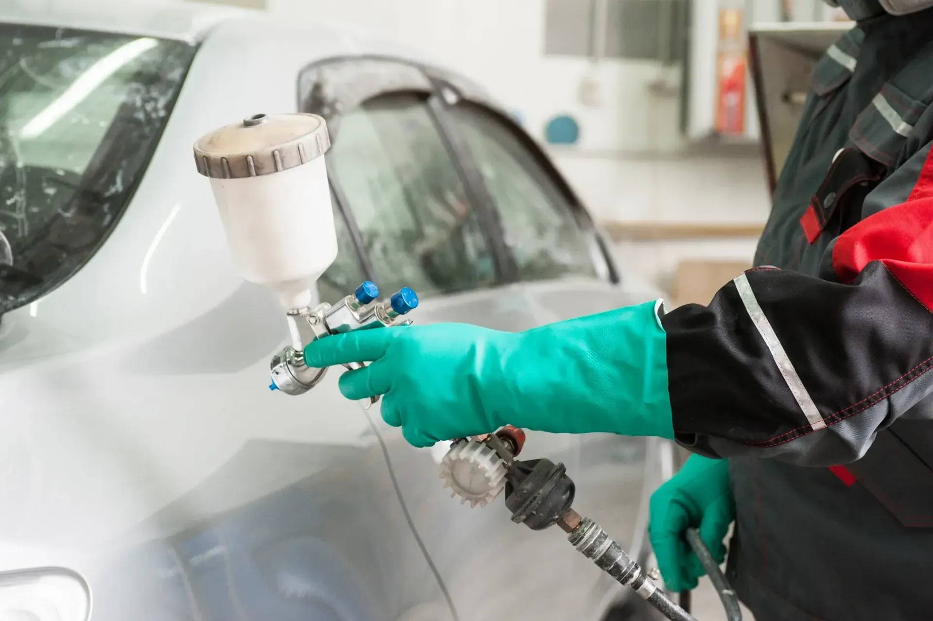 A man is spraying paint on a car in a garage.