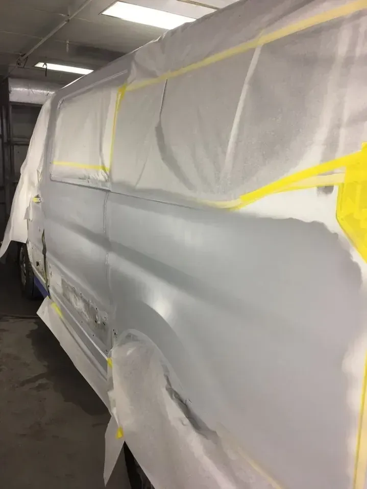 A white van is being painted in a garage.