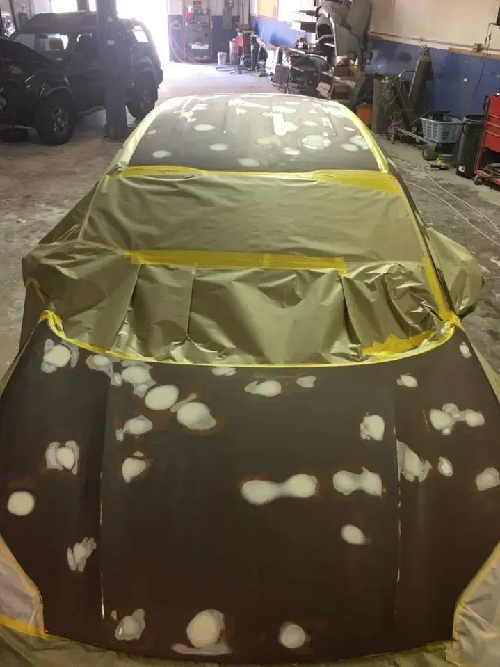 A car is being painted in a garage.