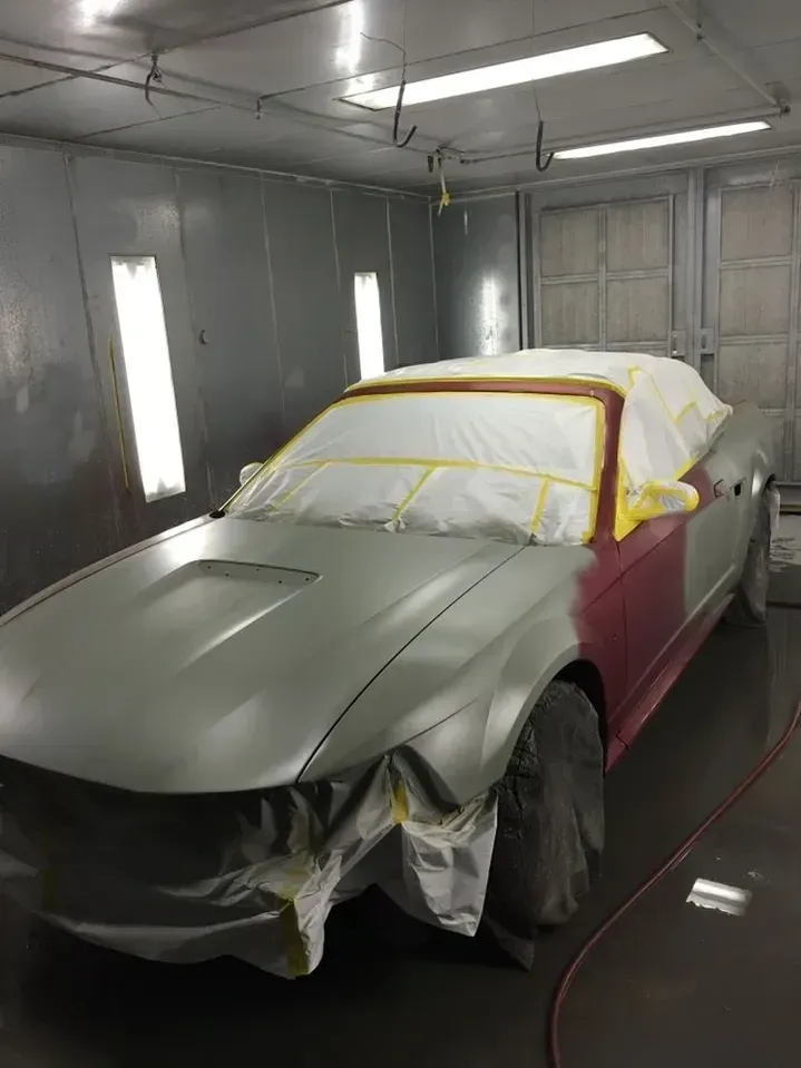 A car is being painted in a paint booth.