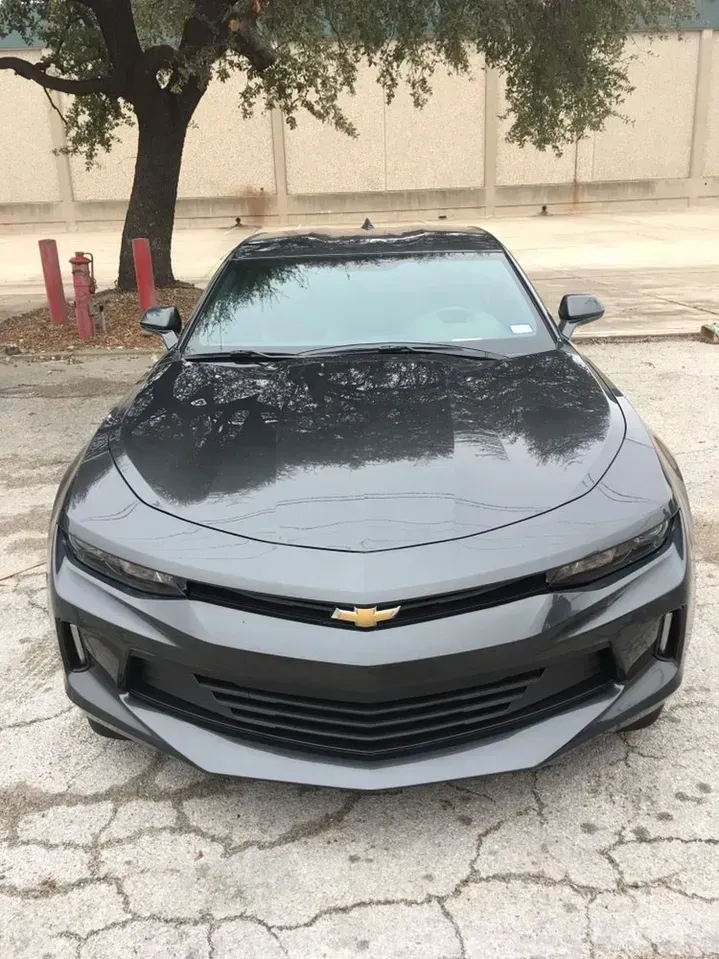 A black chevrolet camaro is parked in a parking lot.