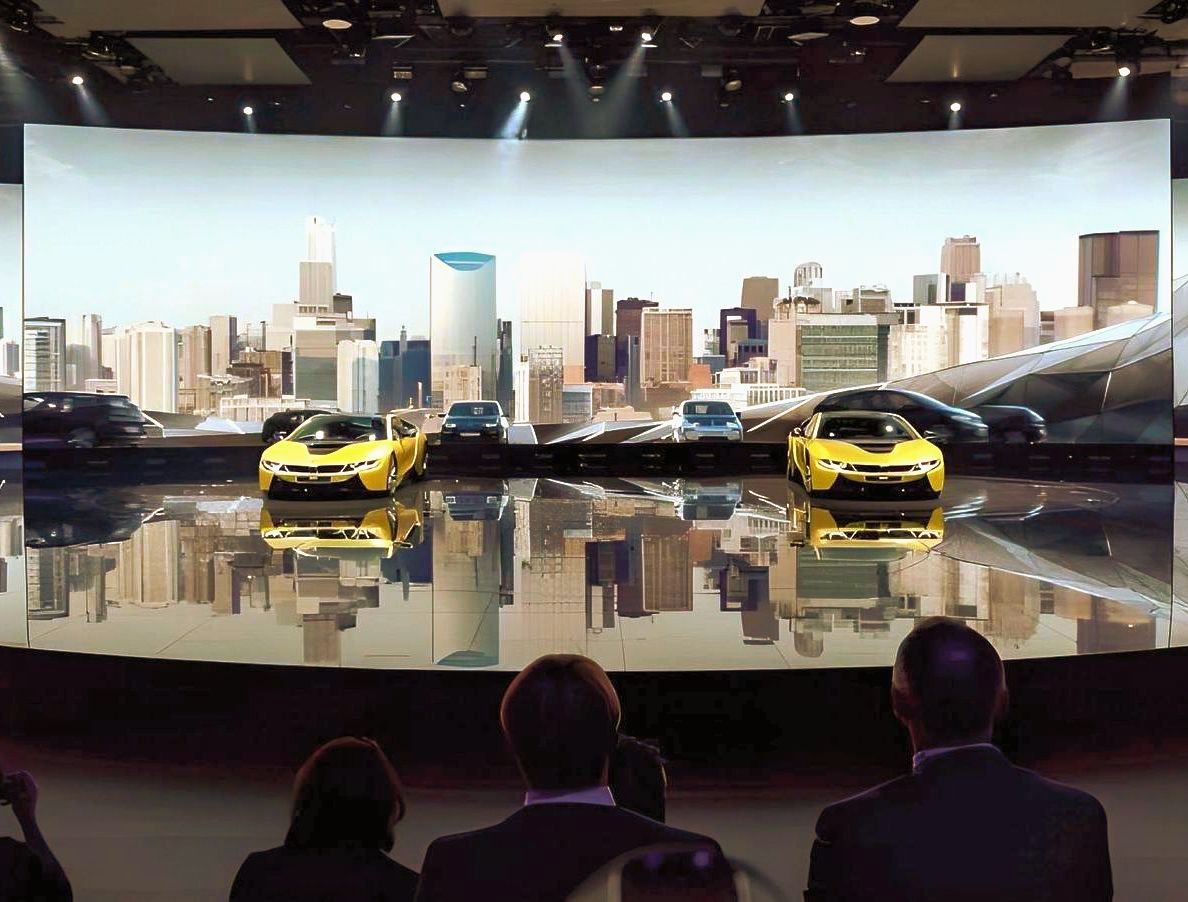 A group of people are watching a car display on a stage.