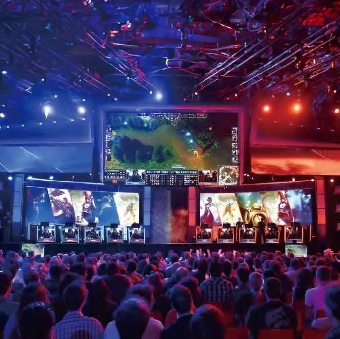 A crowd of people are watching a video game on a large screen