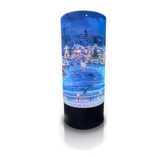 A candle with a picture of a snowy village on it.