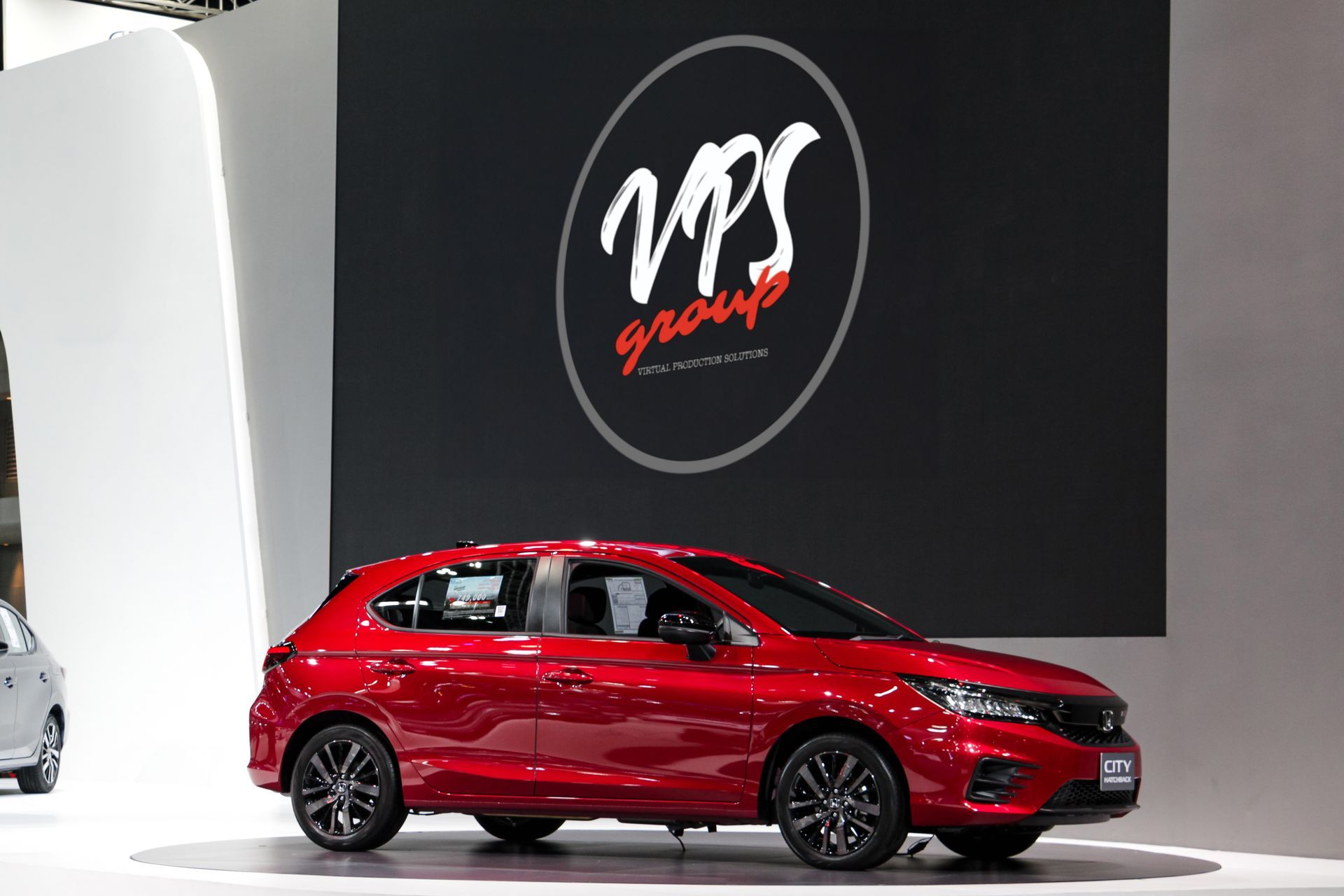 A red car is parked in front of a vps group logo.