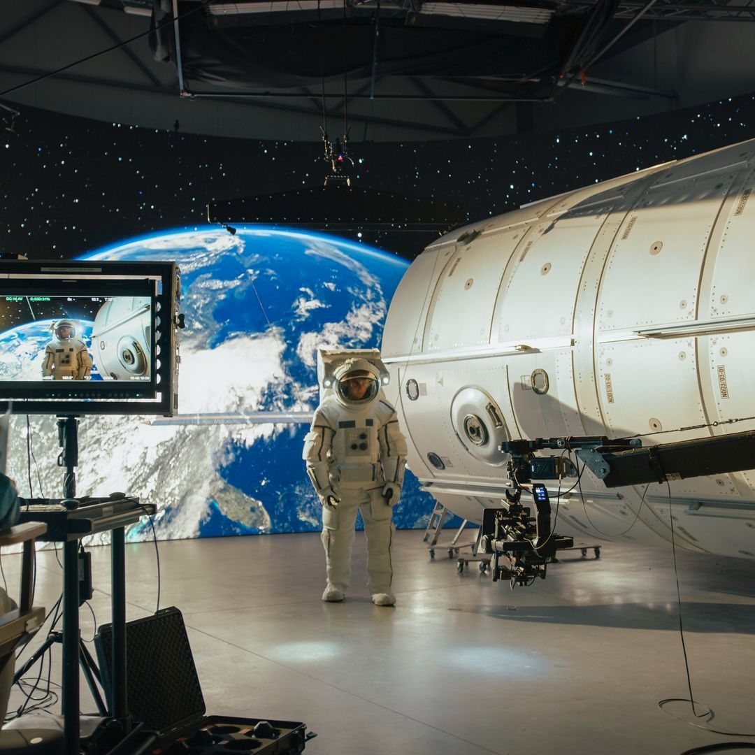 An astronaut is standing in front of a space station