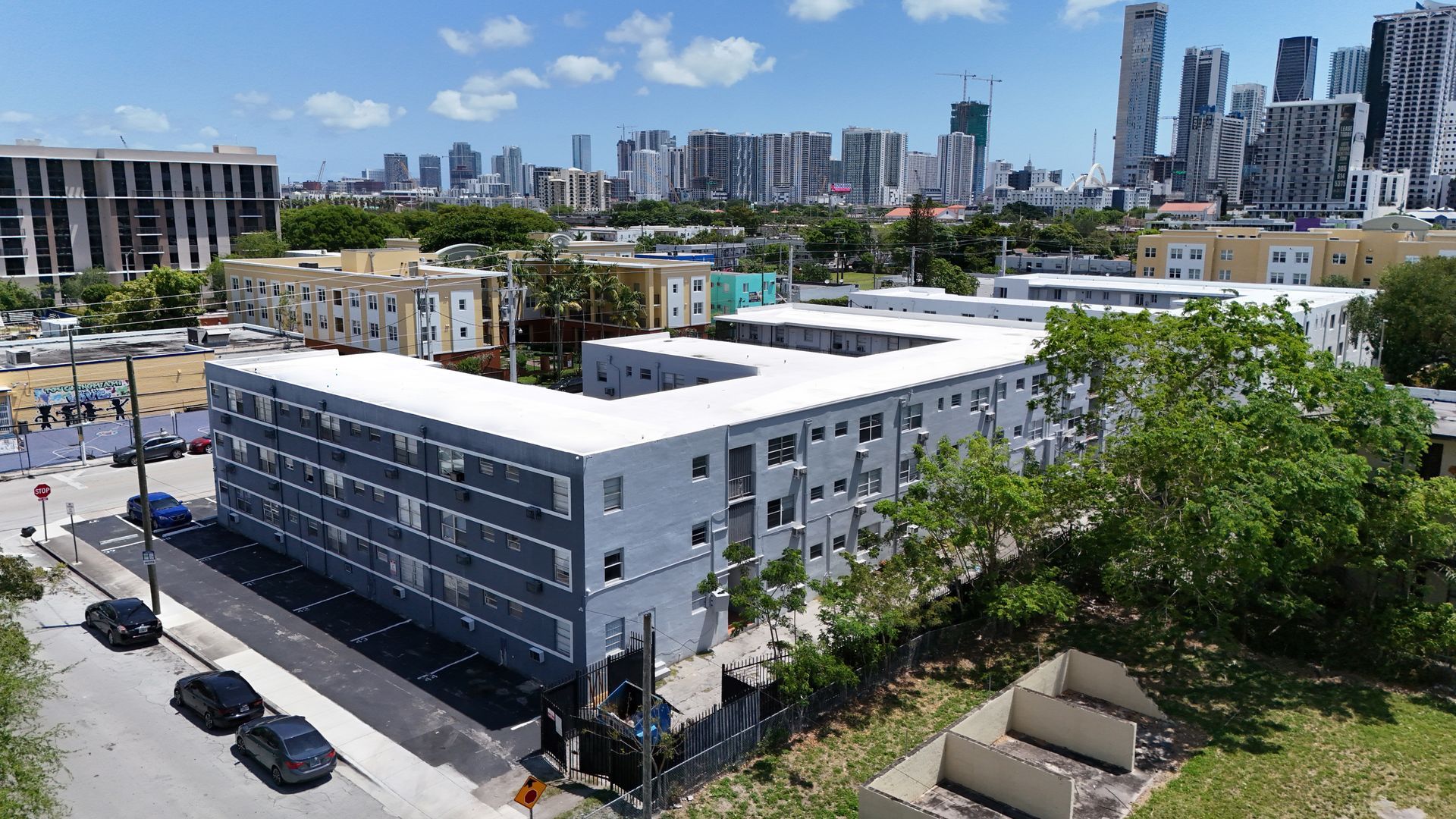 An aerial view of a large apartment building with a city skyline in the background.