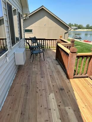 Wooden fence with pointed tops, light brown planks. Outdoor setting with a house in the background.