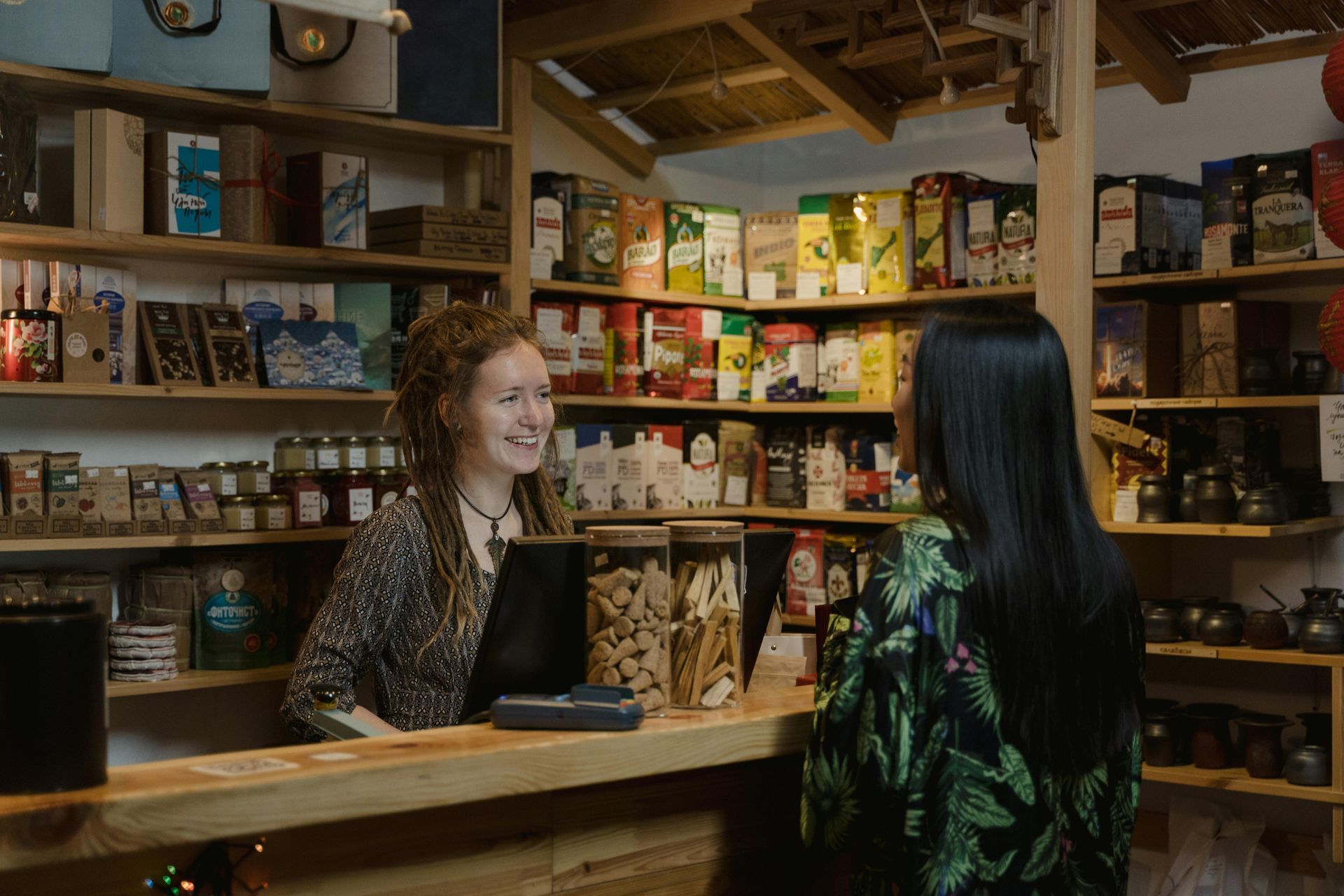A woman at a register speaking to a customer.