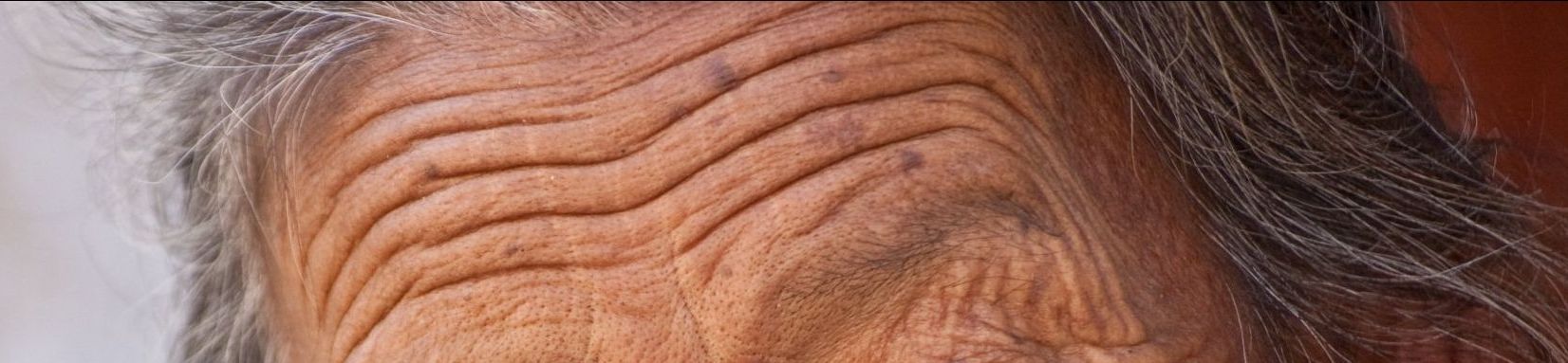 Een close-up van het gezicht van een oudere vrouw met rimpels.