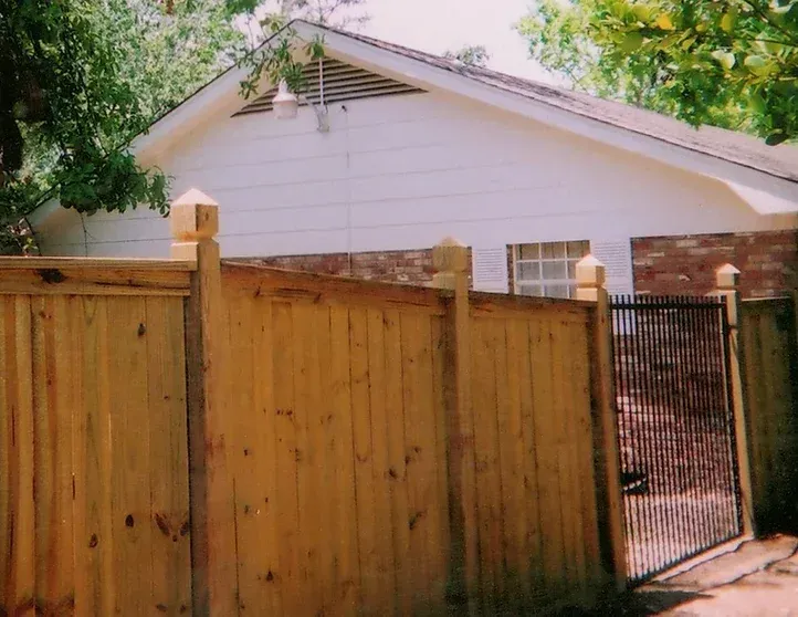 A wooden fence is in front of a white house