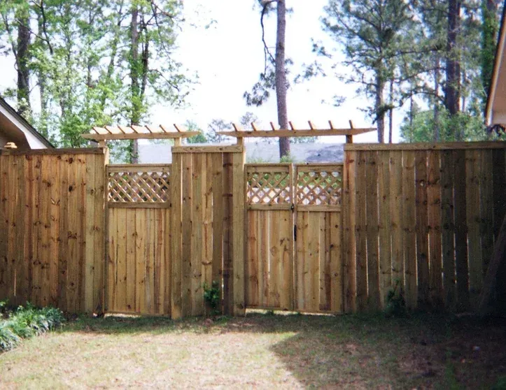 A wooden fence with a gate and trees in the background