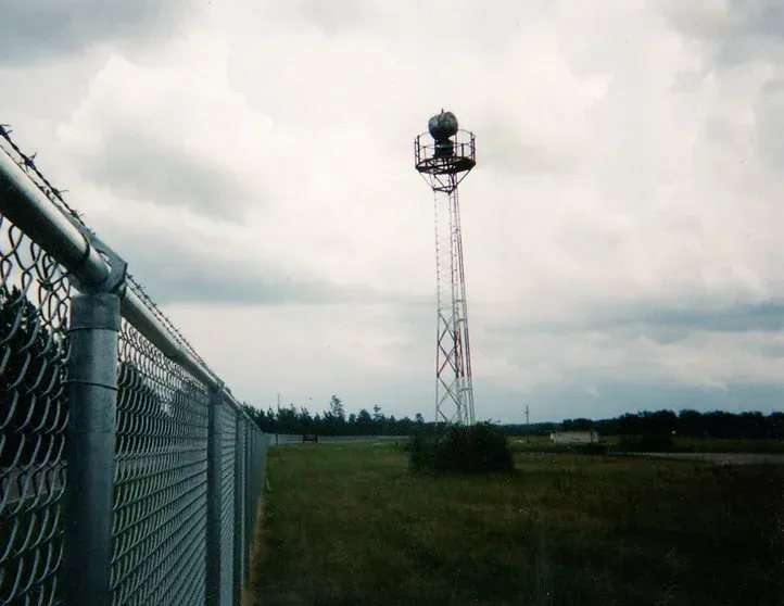 A chain link fence with a tower in the background