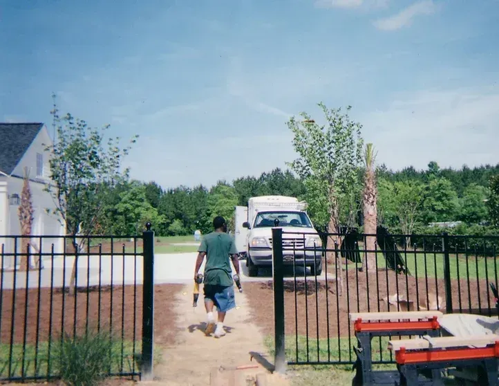 A man is walking towards a truck that is parked in front of a fence.