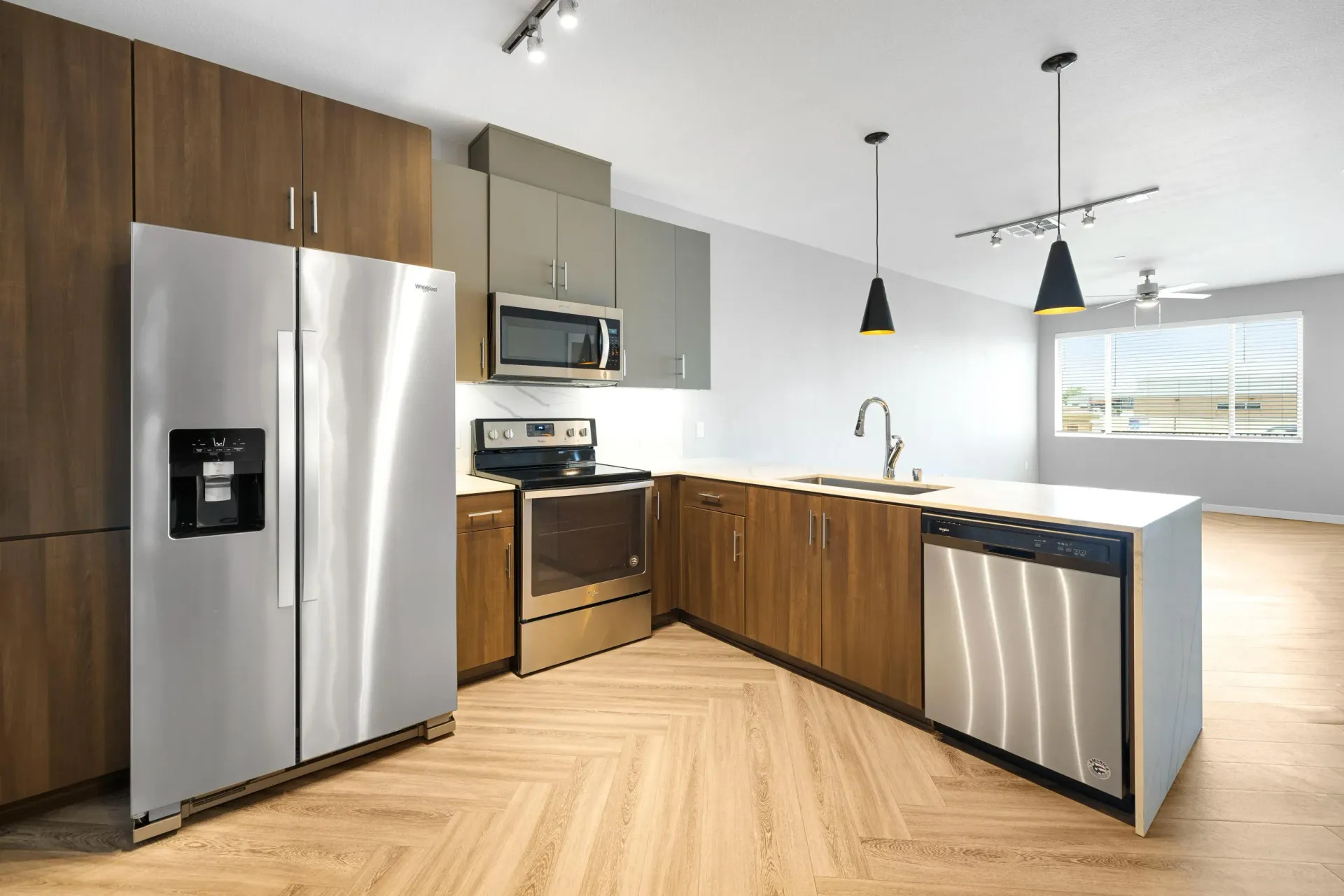 Open-concept kitchen with stainless steel fridge, oven, microwave, dishwasher, and wood cabinets.