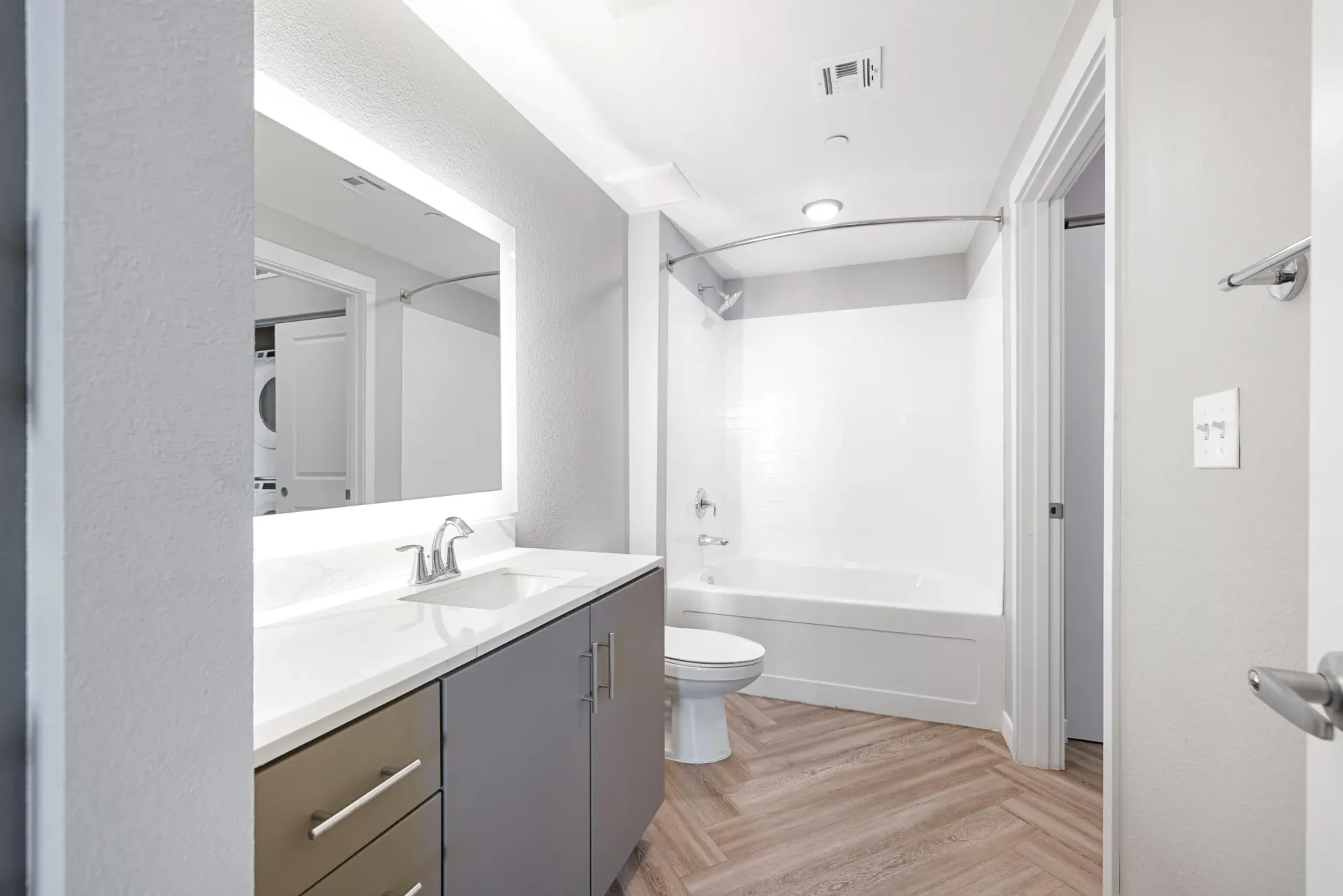 Bathroom in an apartment with vanity, mirror, toilet, and tub/shower.