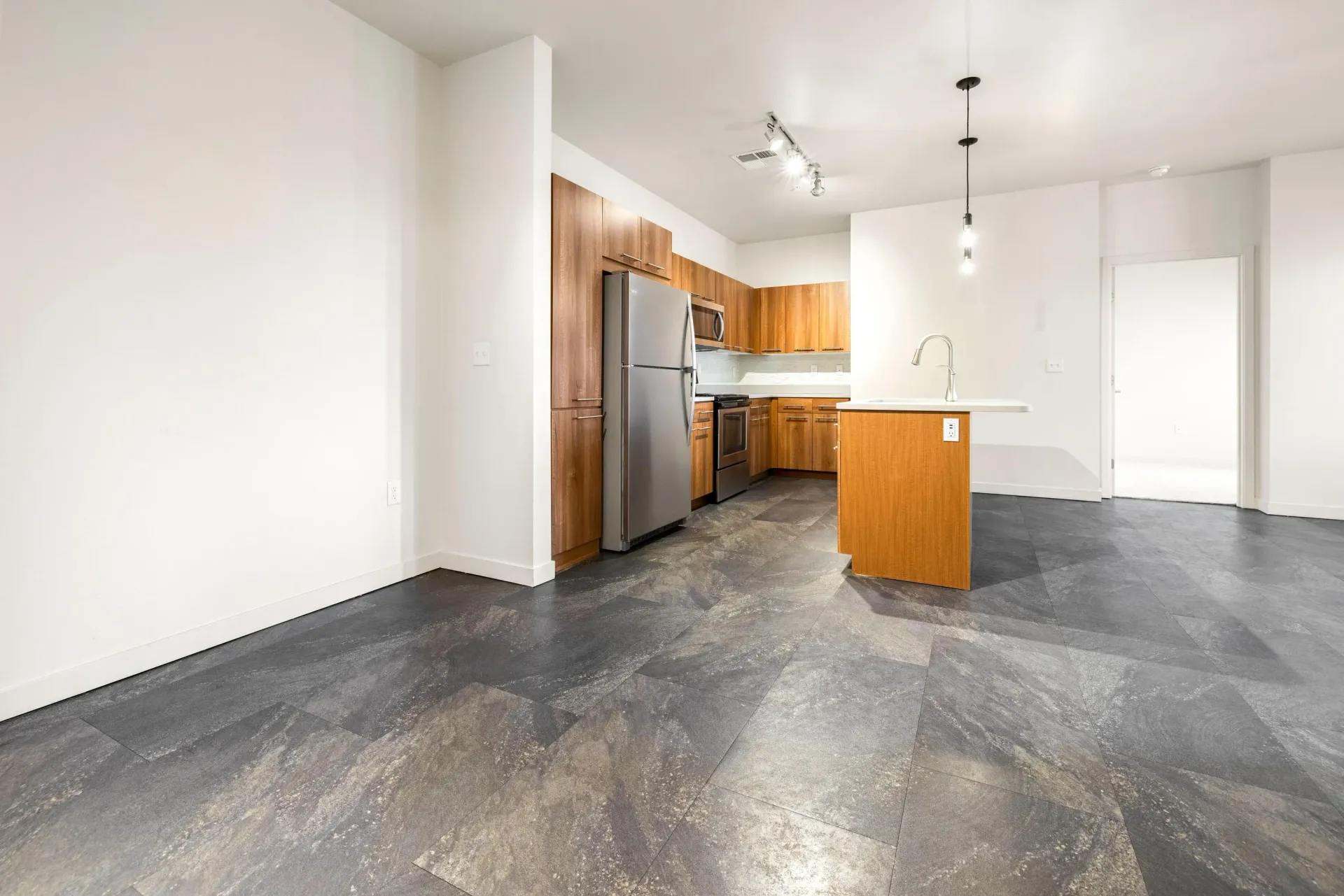 Open-concept kitchen with wood-tone cabinets, stainless steel appliances, and a white island.