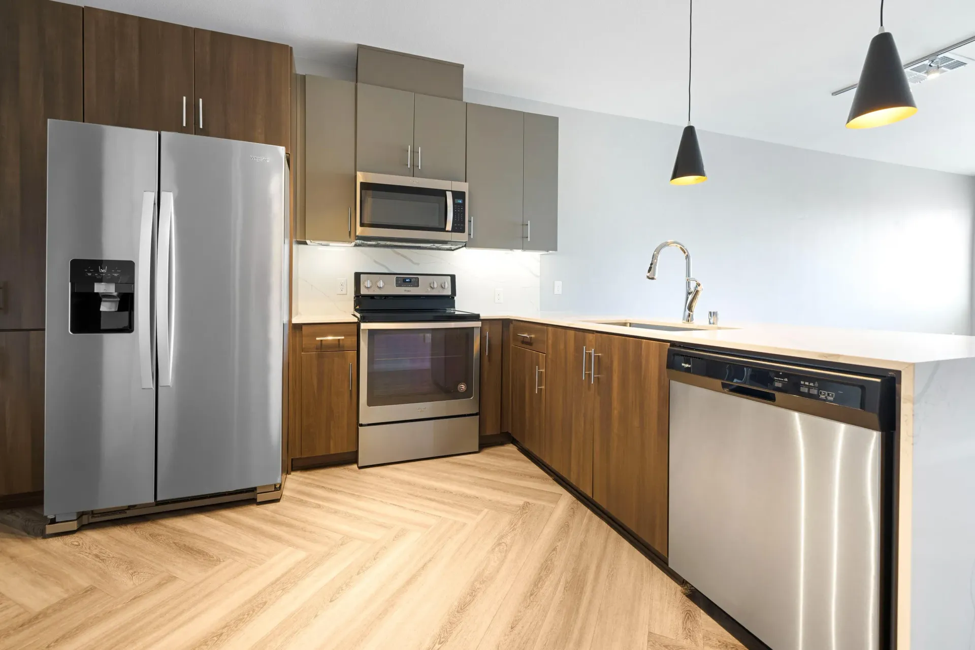 Modern kitchen with stainless steel refrigerator, range, microwave, and dishwasher.