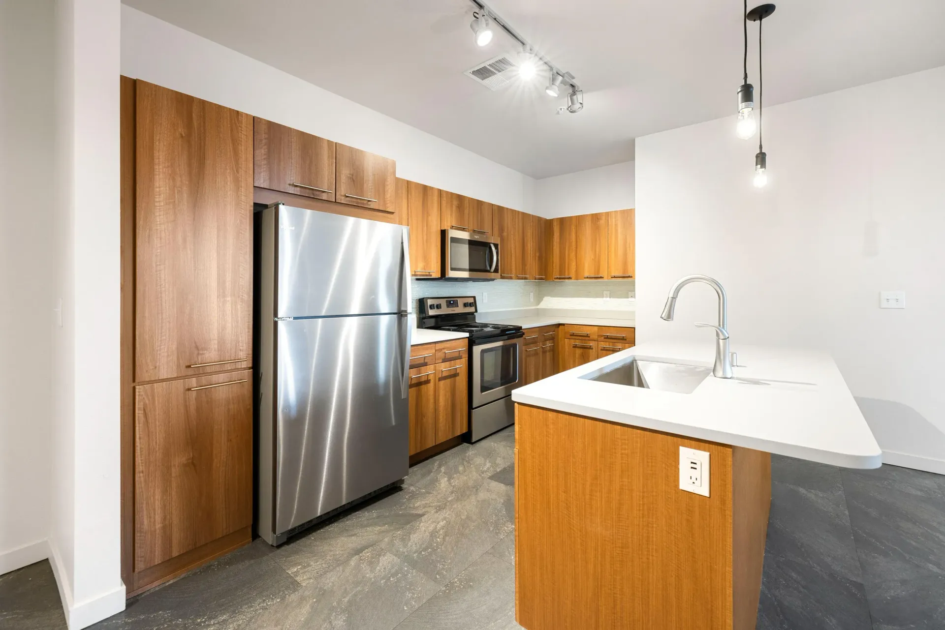 Modern kitchen with wooden cabinets, stainless steel appliances, and a white island with sink.