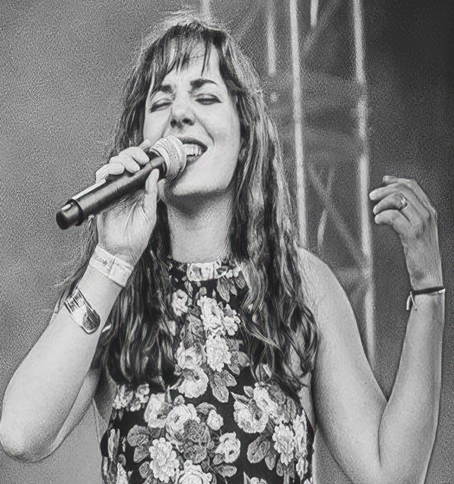 Une femme portant des lunettes et une chemise à carreaux prend un selfie.