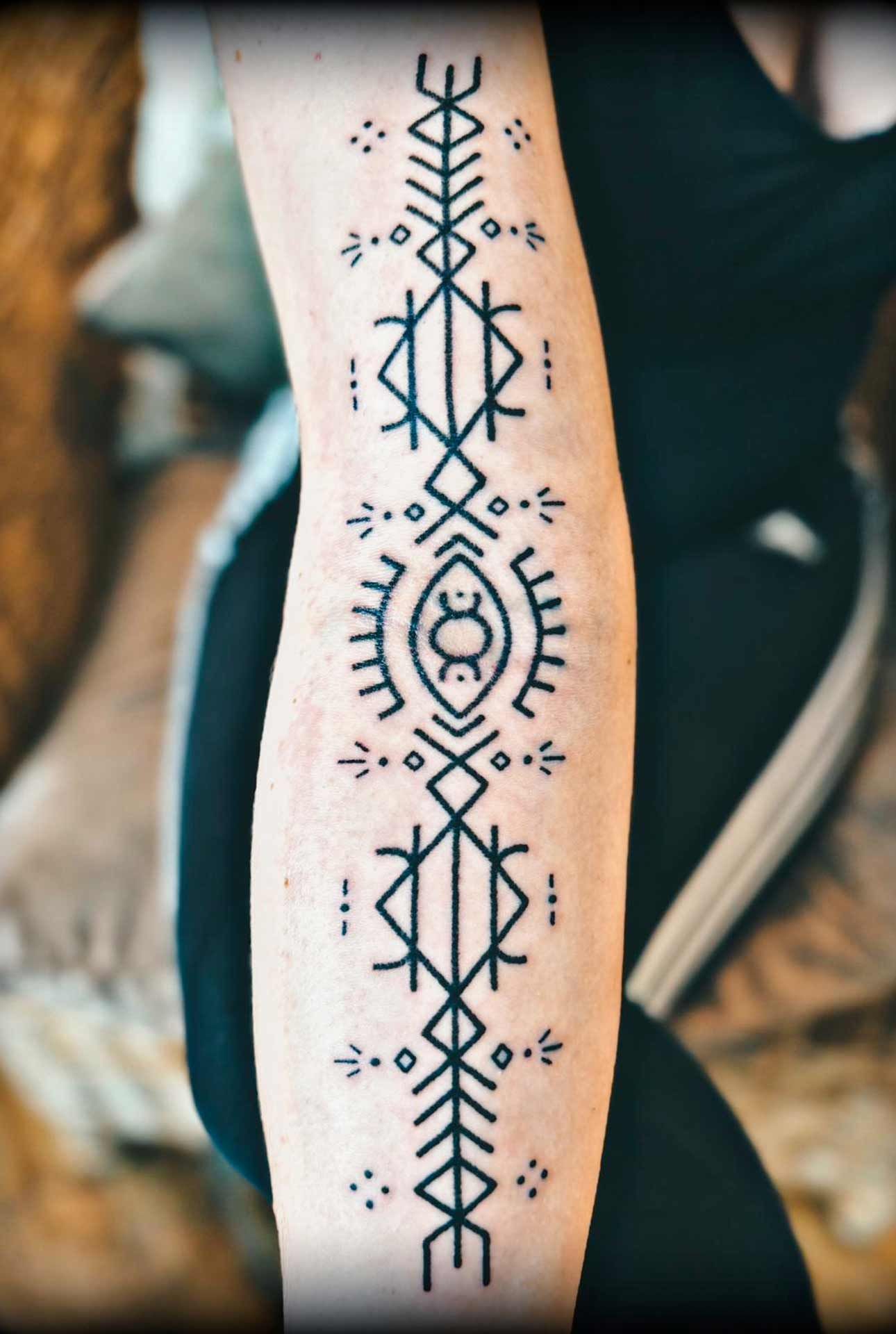 Une personne a un tatouage sur le bras qui ressemble à un motif amérindien