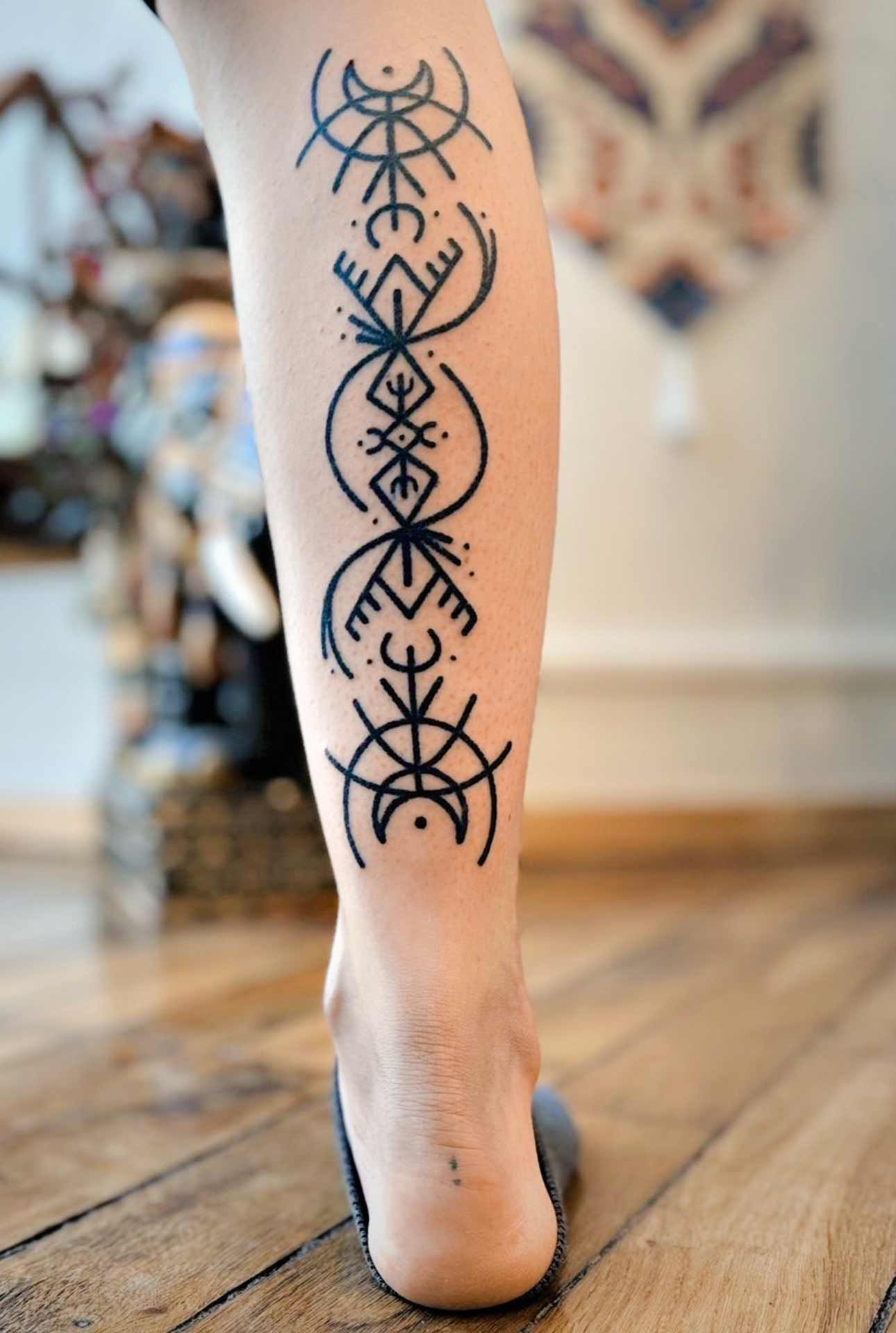 Une personne a un tatouage sur la jambe qui ressemble à un symbole celtique.