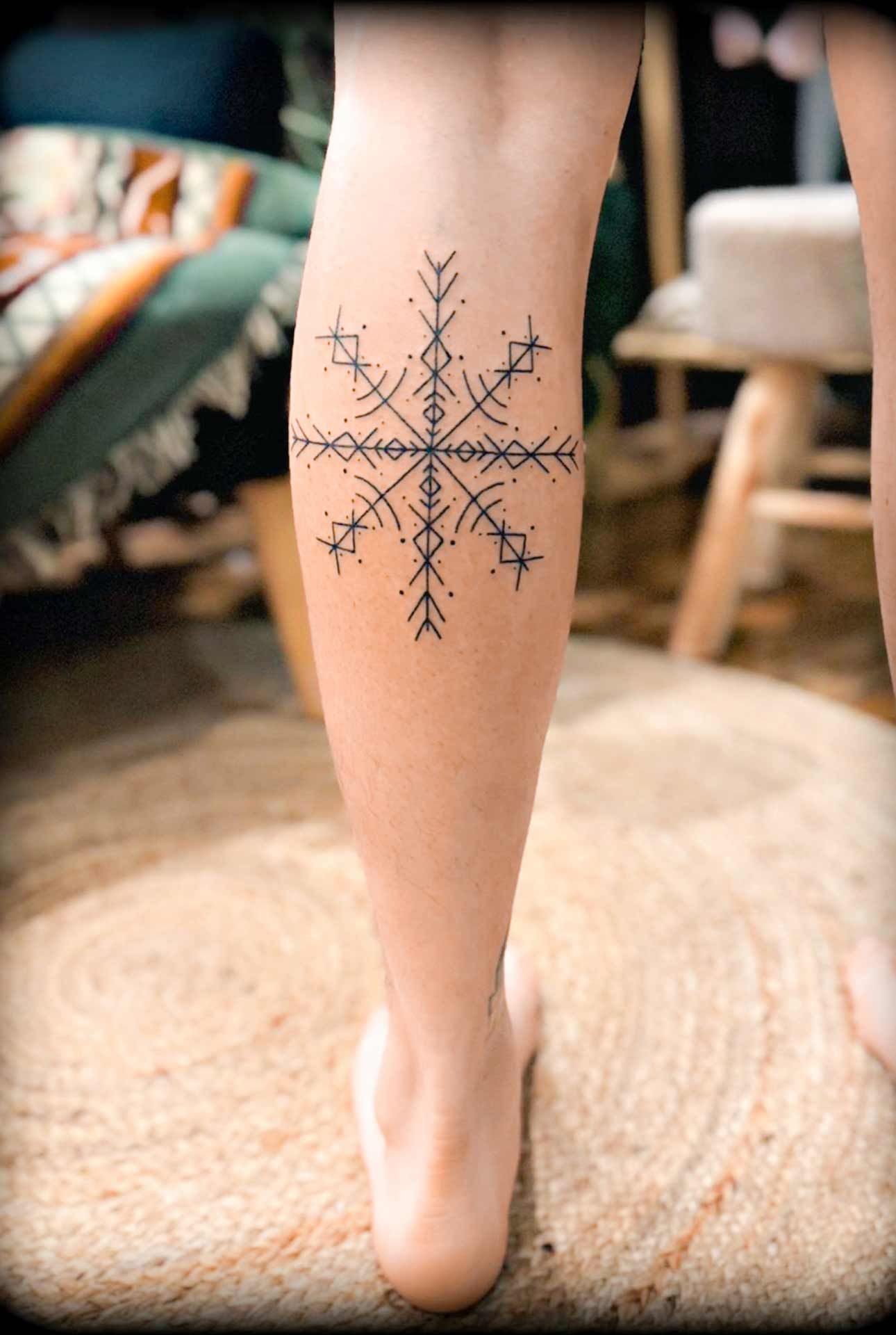 Une femme a un tatouage de flocon de neige sur sa jambe.
