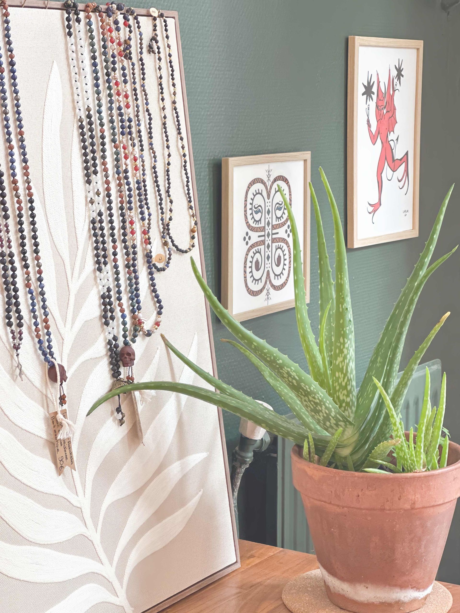 Une plante en pot est posée sur une table à côté d'un tableau et d'un porte-collier.