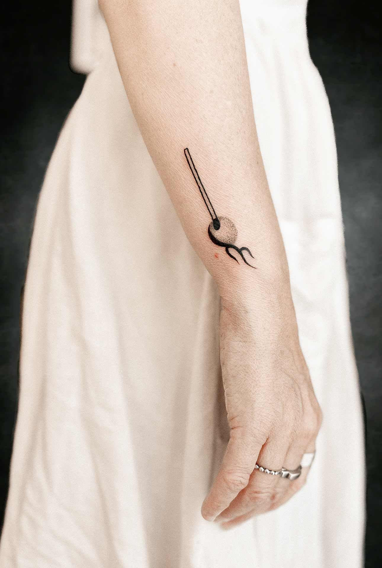 Une femme en robe blanche a un petit tatouage sur son poignet.