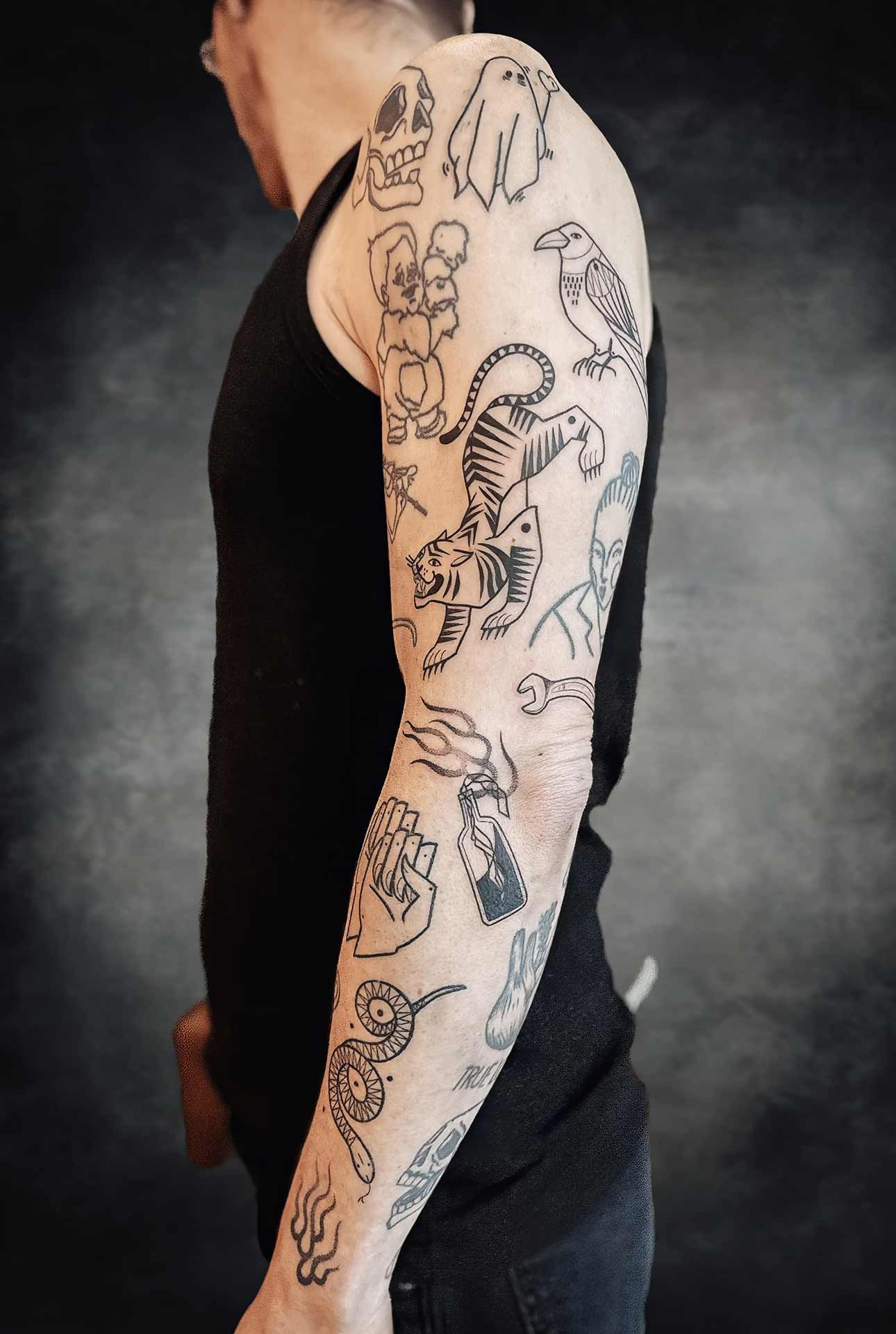 Un homme a de nombreux tatouages ​​sur son bras, dont un tigre et un oiseau