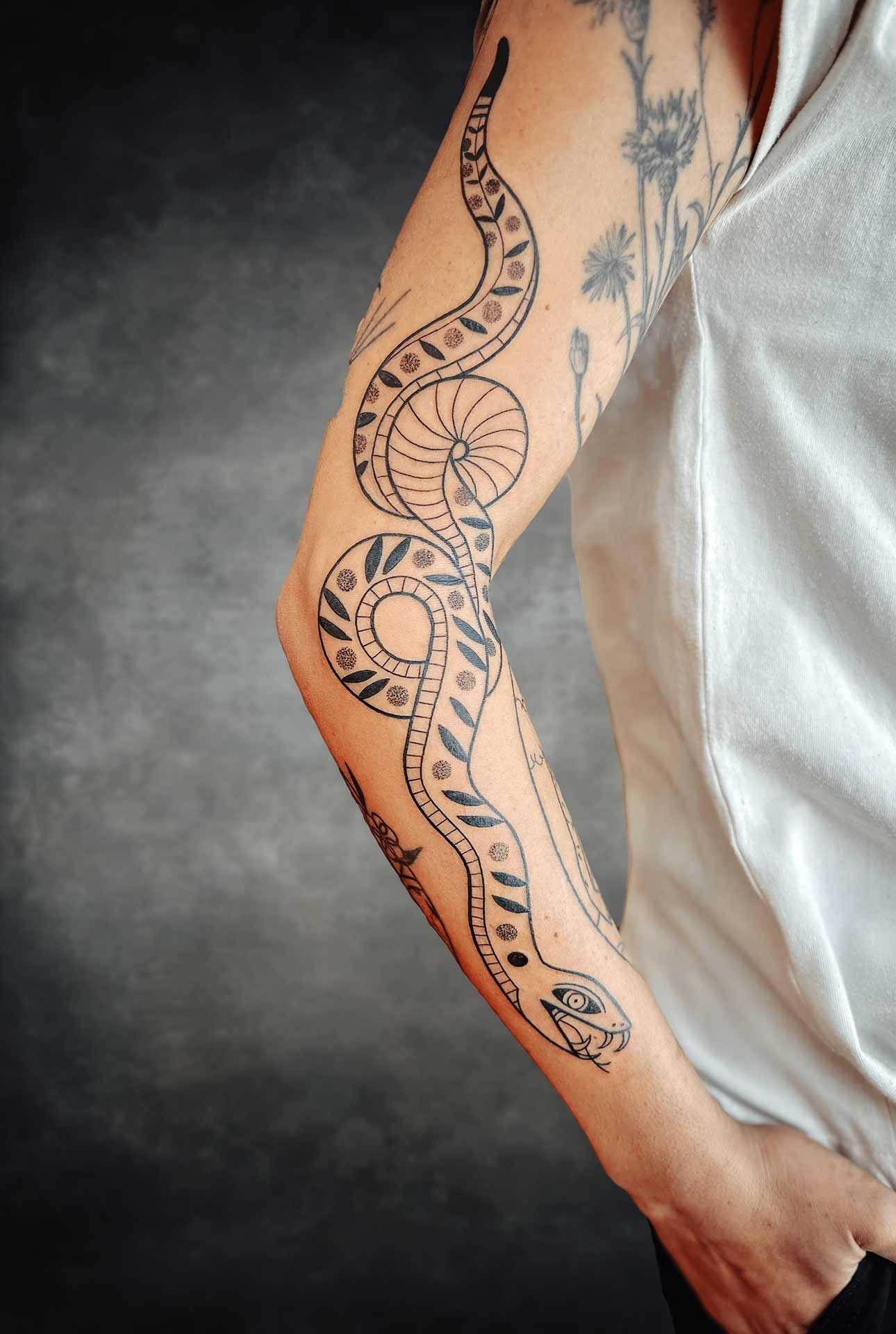 Une personne avec un tatouage de serpent sur le bras