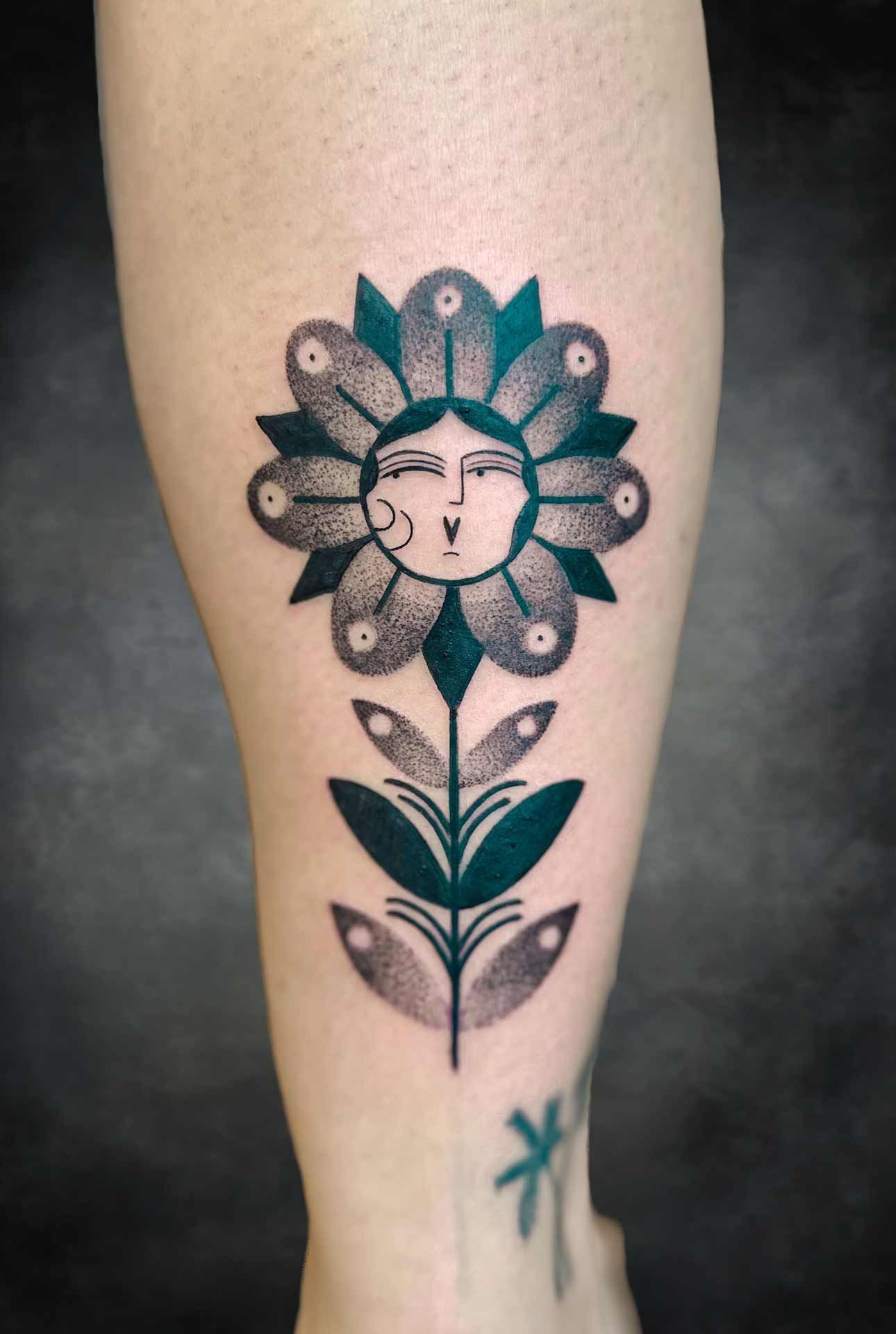 Une personne a un tatouage d'une fleur avec un visage dessus.