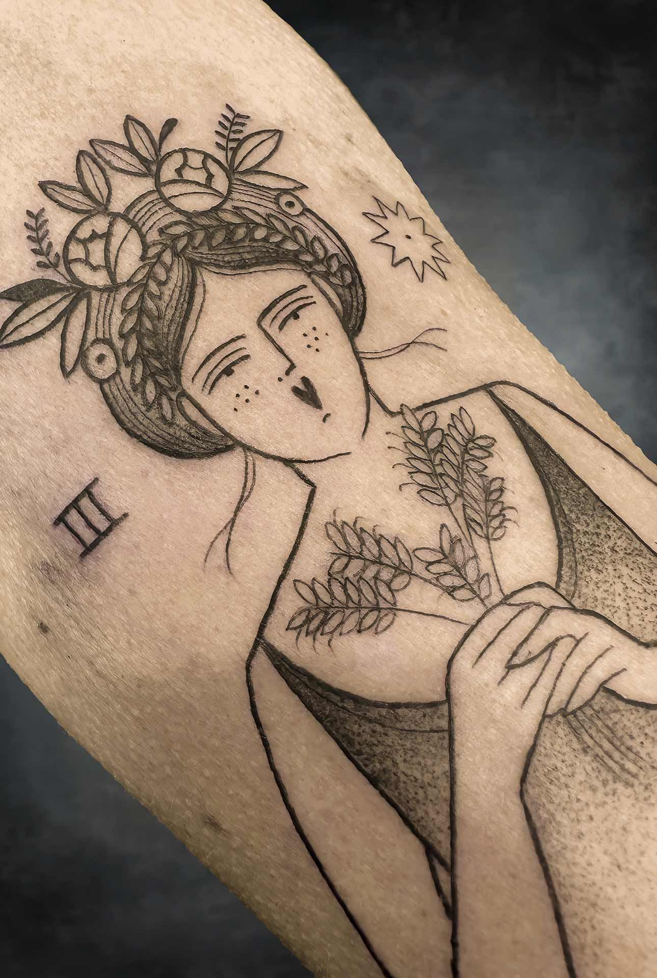 Un tatouage noir et blanc d'une femme avec des fleurs sur la tête.