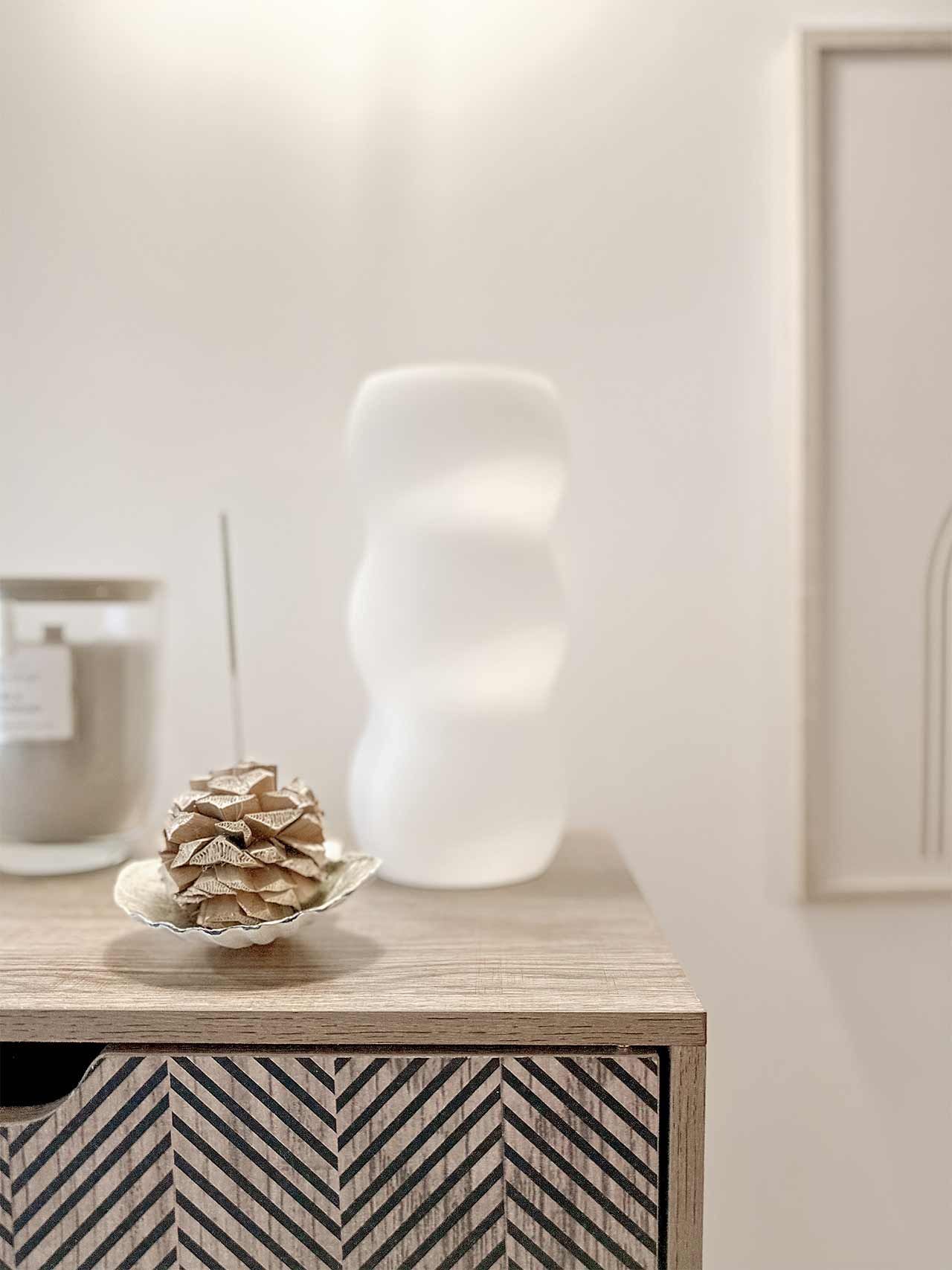 Une table de chevet en bois avec une bougie et un vase dessus.